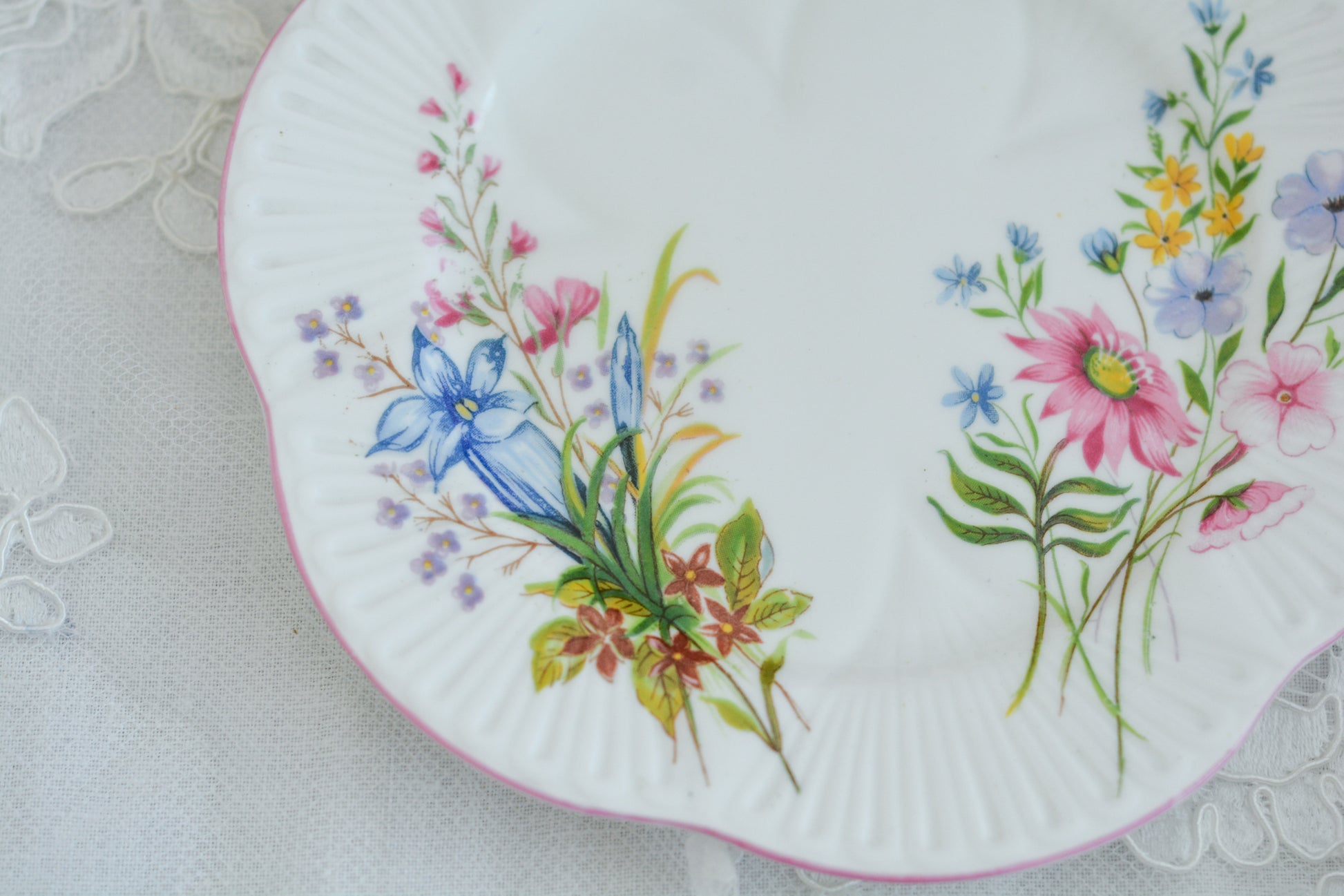 シェリーのワイルドフラワーシリーズの可愛らしいティートリオです。カップはディンティーシェイプと呼ばれる可愛らしいシェイプで上から見るとお花が咲いている様に見えます。イギリスの色とりどりの野花が散りばめられていて、どんな花がプリントされているか眺めるのも楽しいです。こちらは同じシリーズのピンクのお揃いのB&Bプレート、色違いのブルーのB&Bプレートも別で掲載しています。