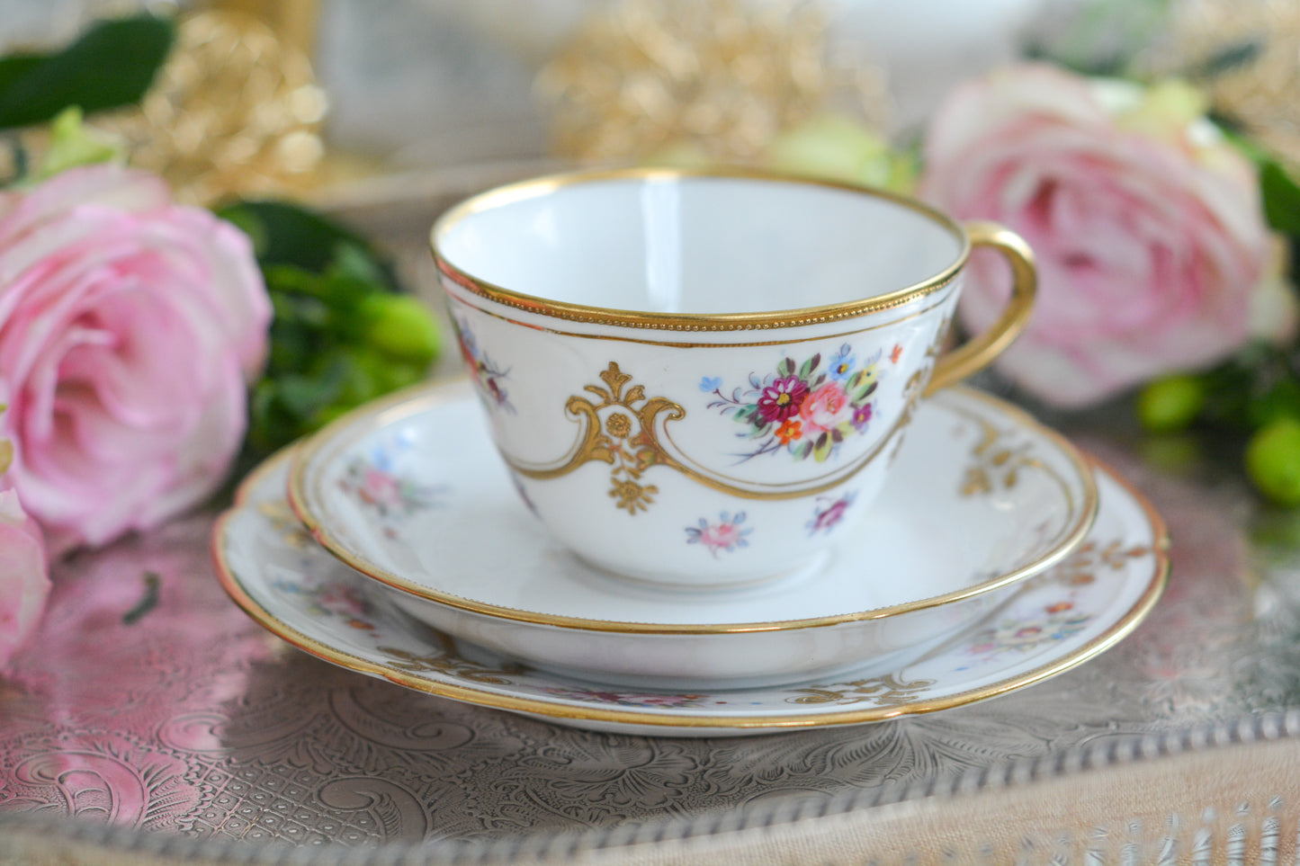 ノリタケの里帰り品のティートリオ。ハンドペイントで描かれた可愛らしいお花に金盛りの金彩の模様もとてもエレガントです。白磁がとても白く美しく気品を感じるお品。クリスマスはもちろんティータイムを華やかに盛り上げてくれるでしょう。