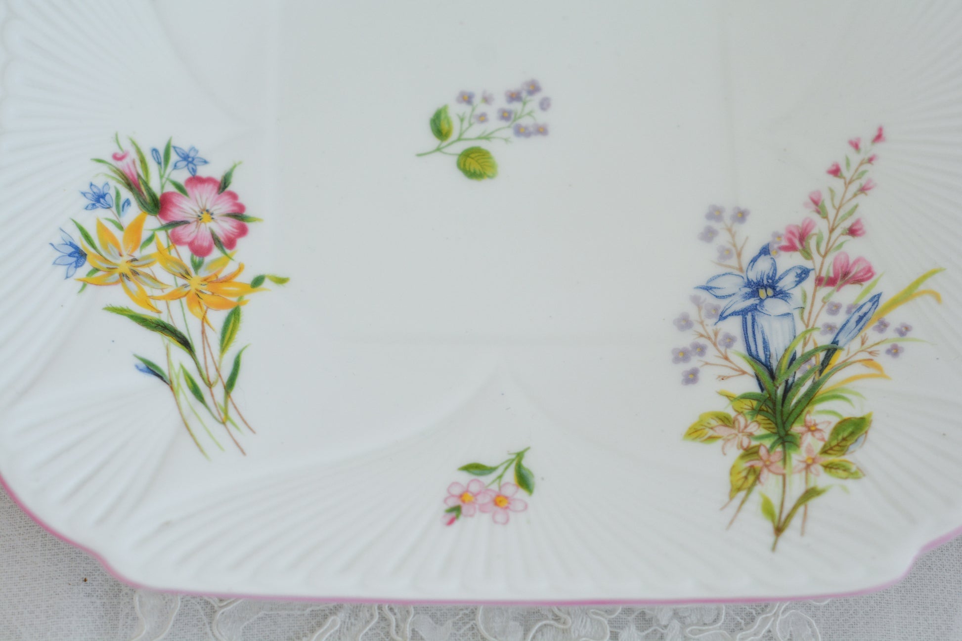 シェリーのワイルドフラワーシリーズの可愛らしいB&Bプレート(ブレッド&バタープレート)。イギリスの色とりどりの野花が散りばめられていて、パステルピンクの縁取りとハンドルがとても可愛らしいお品です。B&Bプレートの「B&B」は「ブレッド&バター」のことでパンやお菓子を盛り付けるのに便利なプレートです。