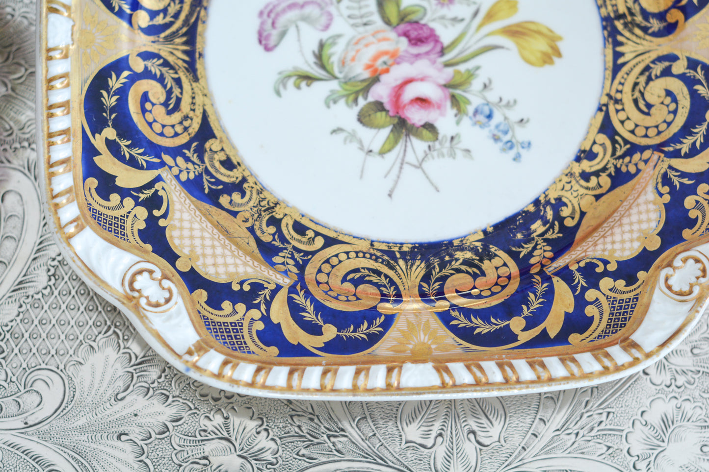 スポードのコバルトブルー地に豪華な金彩模様と手描きで描かれたブーケの模様が美しいプレートです。ちょっと珍しい形をしています。縁の縁飾りのような模様もとても素敵ですね。裏面にはバックスタンプではなく手描きでSpodeと記されています。とても豪華なプレートでキャビネットプレートとして飾ってもとても素敵だなと思います。