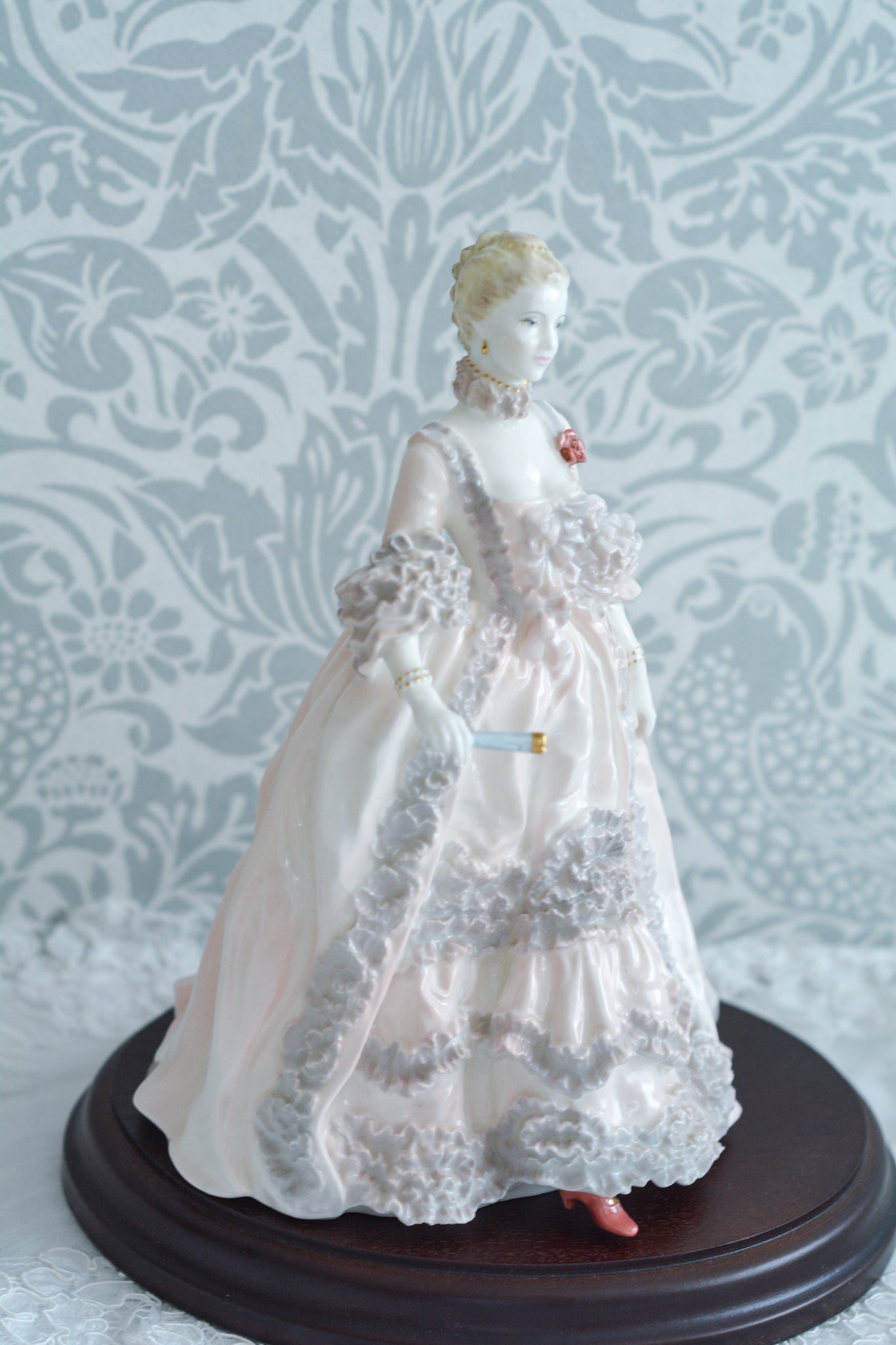 コールポートのポンパドール夫人の美しいフィギュリン。コールポートの中でも一番貴重で人気のフィギュリンではないでしょうか。美しいお顔にグレーとピンクの華やかなドレス。人気があるのも分かります。ポンパドール夫人はその美顔からフランスルイ15世の公式の愛妾となったのは有名な話。美顔だけでなく、頭もとてもよく政治にも積極的に関与しています。色々な側面を持ち合わせますが、芸術を愛し、その発展に大きな影響を与えました。ポンパドール夫人の時代はフランスを中心に優美なロココ様式が流行します。イギリスで1810年〜1830年代頃に流行したロココリバイバルはフランスのロココ様式の影響を受けてイギリスでロココ様式が再流行したものです。そんなポンパドール夫人のフィギュリンは、キャビネットに飾ってもティータイムにテーブルに置いてもどんなシーンでも、パッとスポットライトが当たったかのような存在感です。