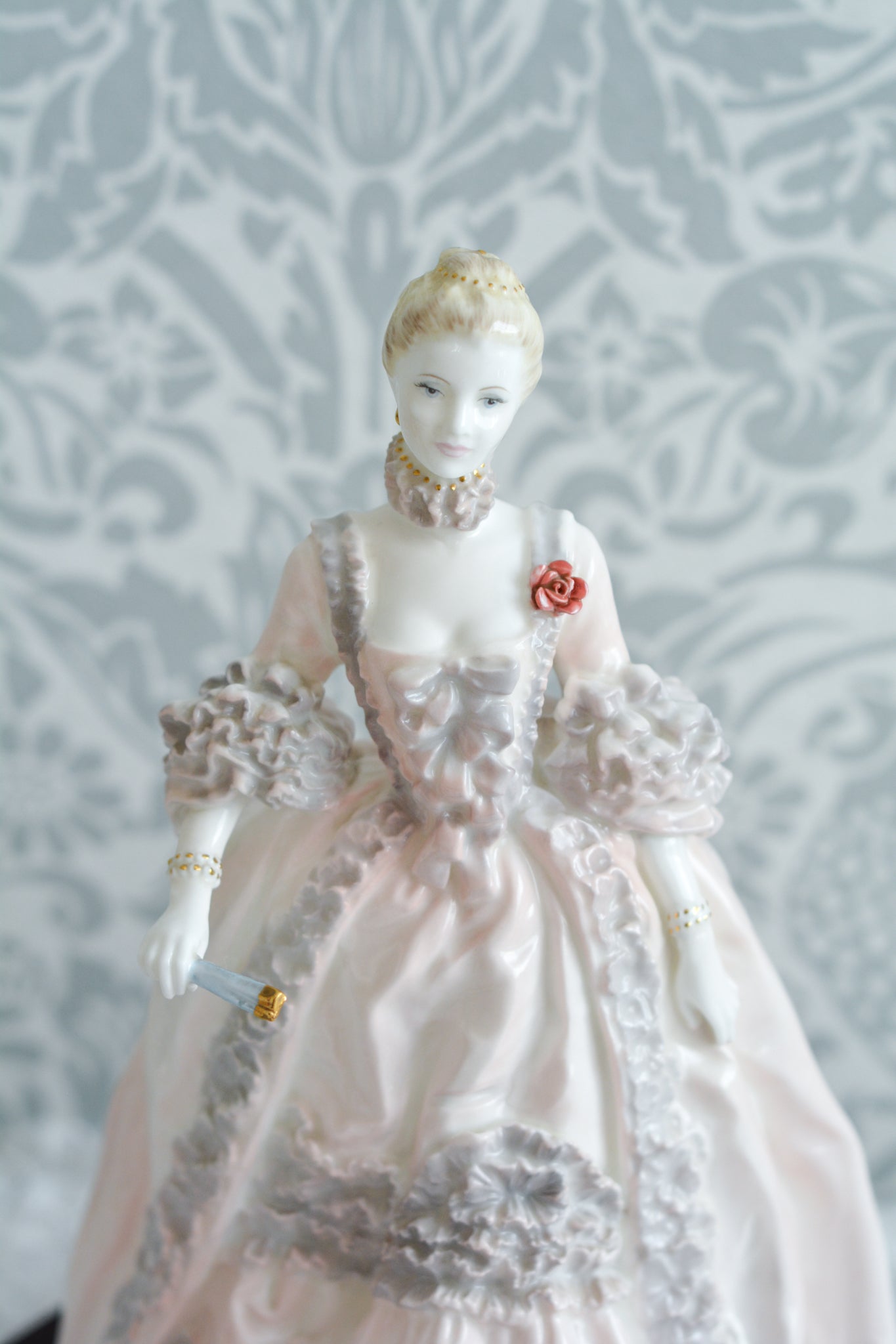 コールポートのポンパドール夫人の美しいフィギュリン。コールポートの中でも一番貴重で人気のフィギュリンではないでしょうか。美しいお顔にグレーとピンクの華やかなドレス。人気があるのも分かります。ポンパドール夫人はその美顔からフランスルイ15世の公式の愛妾となったのは有名な話。美顔だけでなく、頭もとてもよく政治にも積極的に関与しています。色々な側面を持ち合わせますが、芸術を愛し、その発展に大きな影響を与えました。ポンパドール夫人の時代はフランスを中心に優美なロココ様式が流行します。イギリスで1810年〜1830年代頃に流行したロココリバイバルはフランスのロココ様式の影響を受けてイギリスでロココ様式が再流行したものです。そんなポンパドール夫人のフィギュリンは、キャビネットに飾ってもティータイムにテーブルに置いてもどんなシーンでも、パッとスポットライトが当たったかのような存在感です。