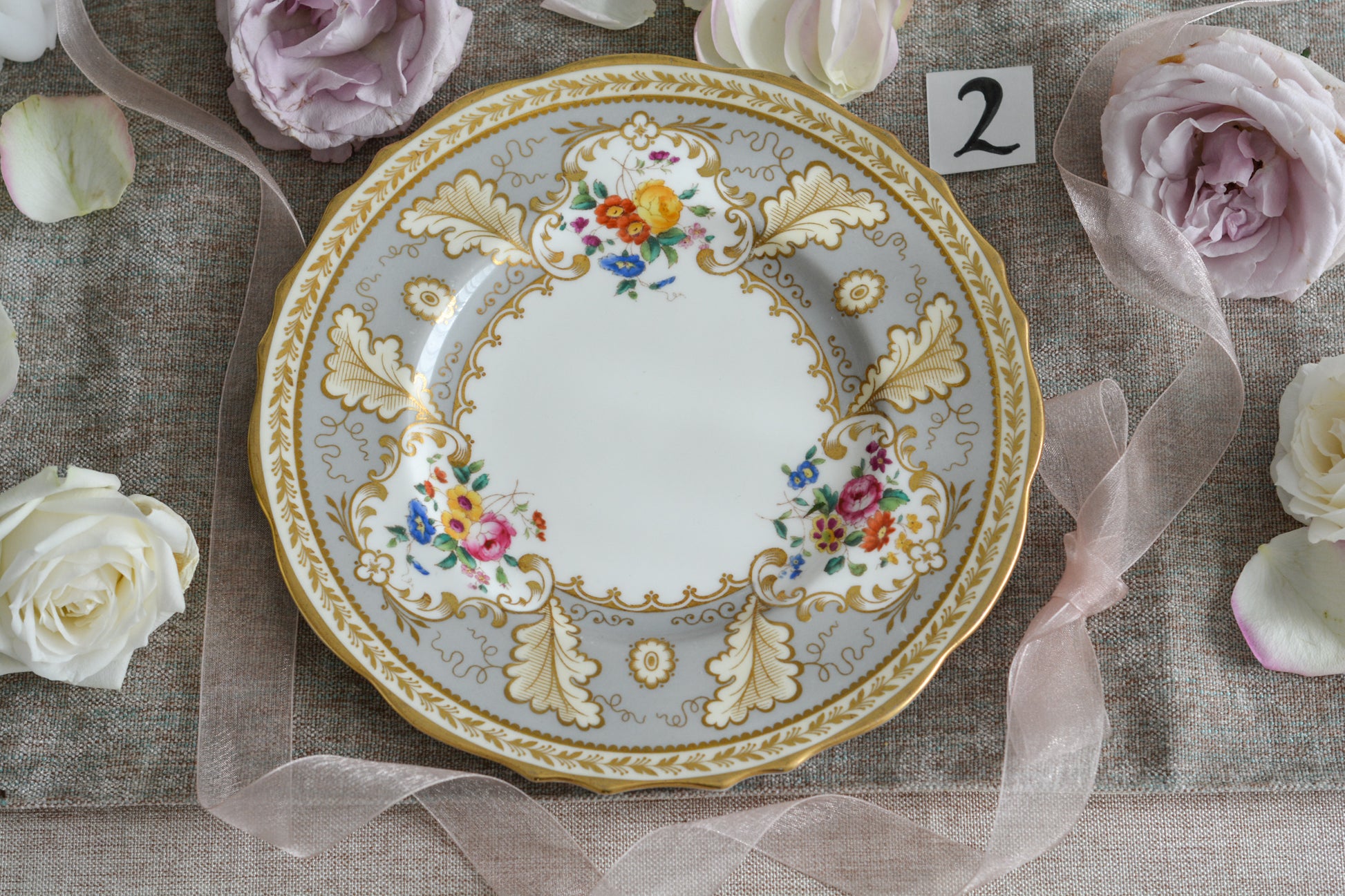 コウルドンのティファニーパターンの素敵なデザートプレートです。ハロッズがオーダーしたもので、ティファニーのスタンプはありませんが、柄はティファニーがコウルドンに特注したパターンです。ティファニーらしい上品な絵柄がとても美しくでコウルドンの中でも人気のシリーズです。当時も人気があったのでしょう。いろいろな小売店がこのパターンをオーダーしています。グレーカラーは柔らかい雰囲気で金彩との相性もいいです。とてもエレガントなプレートです。