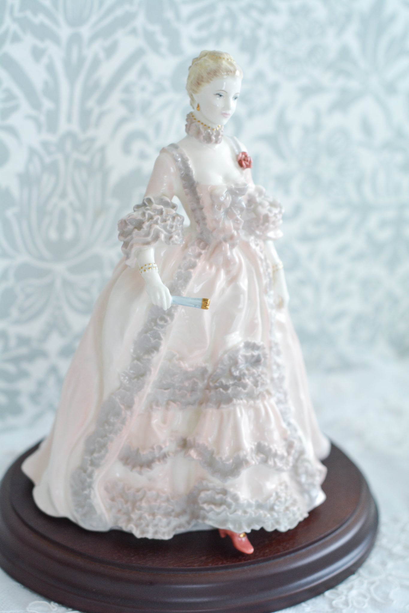 コールポートのポンパドール夫人の美しいフィギュリン。コールポートの中でも一番貴重で人気のフィギュリンではないでしょうか。美しいお顔にグレーとピンクの華やかなドレス。人気があるのも分かります。ポンパドール夫人はその美顔からフランスルイ15世の公式の愛妾となったのは有名な話。美顔だけでなく、頭もとてもよく政治にも積極的に関与しています。色々な側面を持ち合わせますが、芸術を愛し、その発展に大きな影響を与えました。ポンパドール夫人の時代はフランスを中心に優美なロココ様式が流行します。イギリスで1810年〜1830年代頃に流行したロココリバイバルはフランスのロココ様式の影響を受けてイギリスでロココ様式が再流行したものです。そんなポンパドール夫人のフィギュリンは、キャビネットに飾ってもティータイムにテーブルに置いてもどんなシーンでも、パッとスポットライトが当たったかのような存在感です。