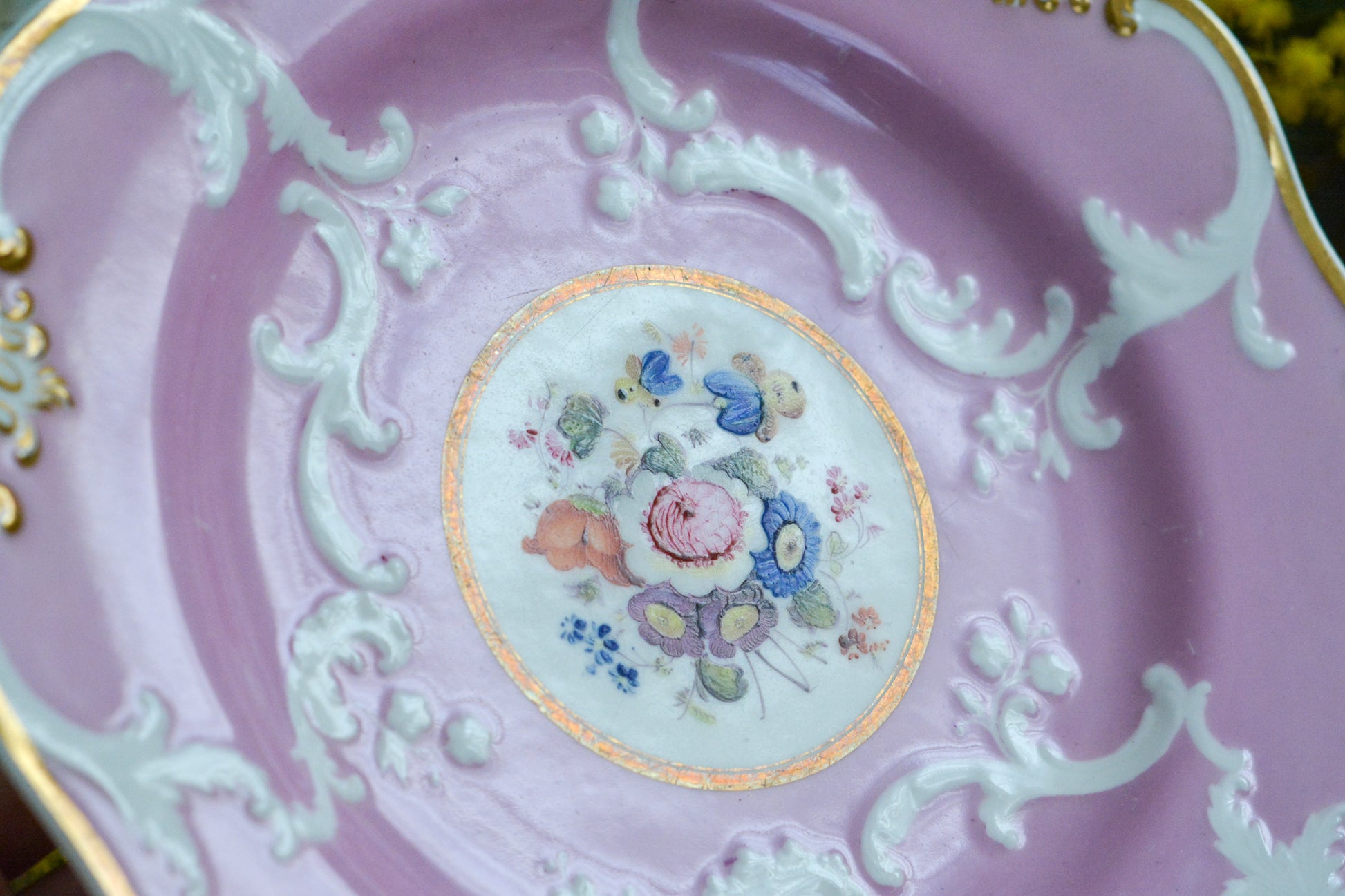 可愛らしいピンクカラーに中央にハンドペイントで丁寧に描かれたブーケの模様が美しいプレートです。エンボスの模様も優雅でチョコレートや小さな焼き菓子、パンどんなものを盛り付けても品よくまとまりそうです。一ヶ所小さなヘアラインがあるためお値打ち価格になっています。