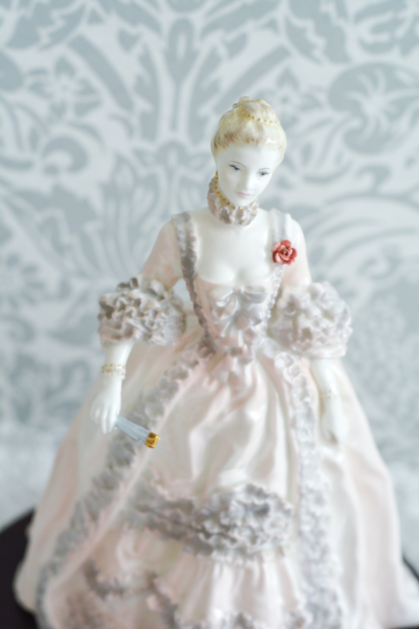 コールポートのポンパドール夫人の美しいフィギュリン。コールポートの中でも一番貴重で人気のフィギュリンではないでしょうか。美しいお顔にグレーとピンクの華やかなドレス。人気があるのも分かります。ポンパドール夫人はその美顔からフランスルイ15世の公式の愛妾となったのは有名な話。美顔だけでなく、頭もとてもよく政治にも積極的に関与しています。色々な側面を持ち合わせますが、芸術を愛し、その発展に大きな影響を与えました。ポンパドール夫人の時代はフランスを中心に優美なロココ様式が流行します。イギリスで1810年〜1830年代頃に流行したロココリバイバルはフランスのロココ様式の影響を受けてイギリスでロココ様式が再流行したものです。そんなポンパドール夫人のフィギュリンは、キャビネットに飾ってもティータイムにテーブルに置いてもどんなシーンでも、パッとスポットライトが当たったかのような存在感です。