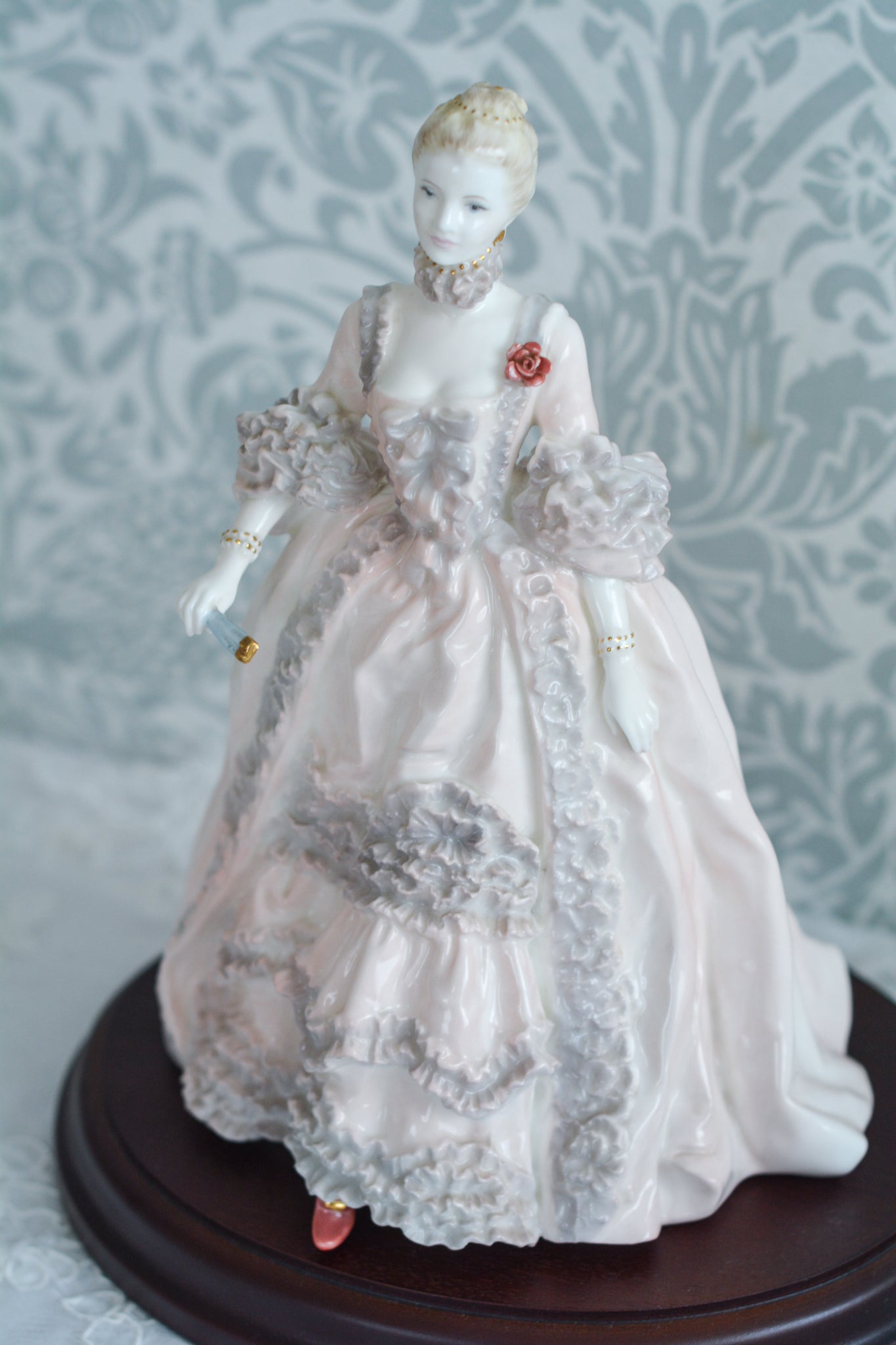 コールポートのポンパドール夫人の美しいフィギュリン。コールポートの中でも一番貴重で人気のフィギュリンではないでしょうか。美しいお顔にグレーとピンクの華やかなドレス。人気があるのも分かります。ポンパドール夫人はその美顔からフランスルイ15世の公式の愛妾となったのは有名な話。美顔だけでなく、頭もとてもよく政治にも積極的に関与しています。色々な側面を持ち合わせますが、芸術を愛し、その発展に大きな影響を与えました。ポンパドール夫人の時代はフランスを中心に優美なロココ様式が流行します。イギリスで1810年〜1830年代頃に流行したロココリバイバルはフランスのロココ様式の影響を受けてイギリスでロココ様式が再流行したものです。そんなポンパドール夫人のフィギュリンは、キャビネットに飾ってもティータイムにテーブルに置いてもどんなシーンでも、パッとスポットライトが当たったかのような存在感です。