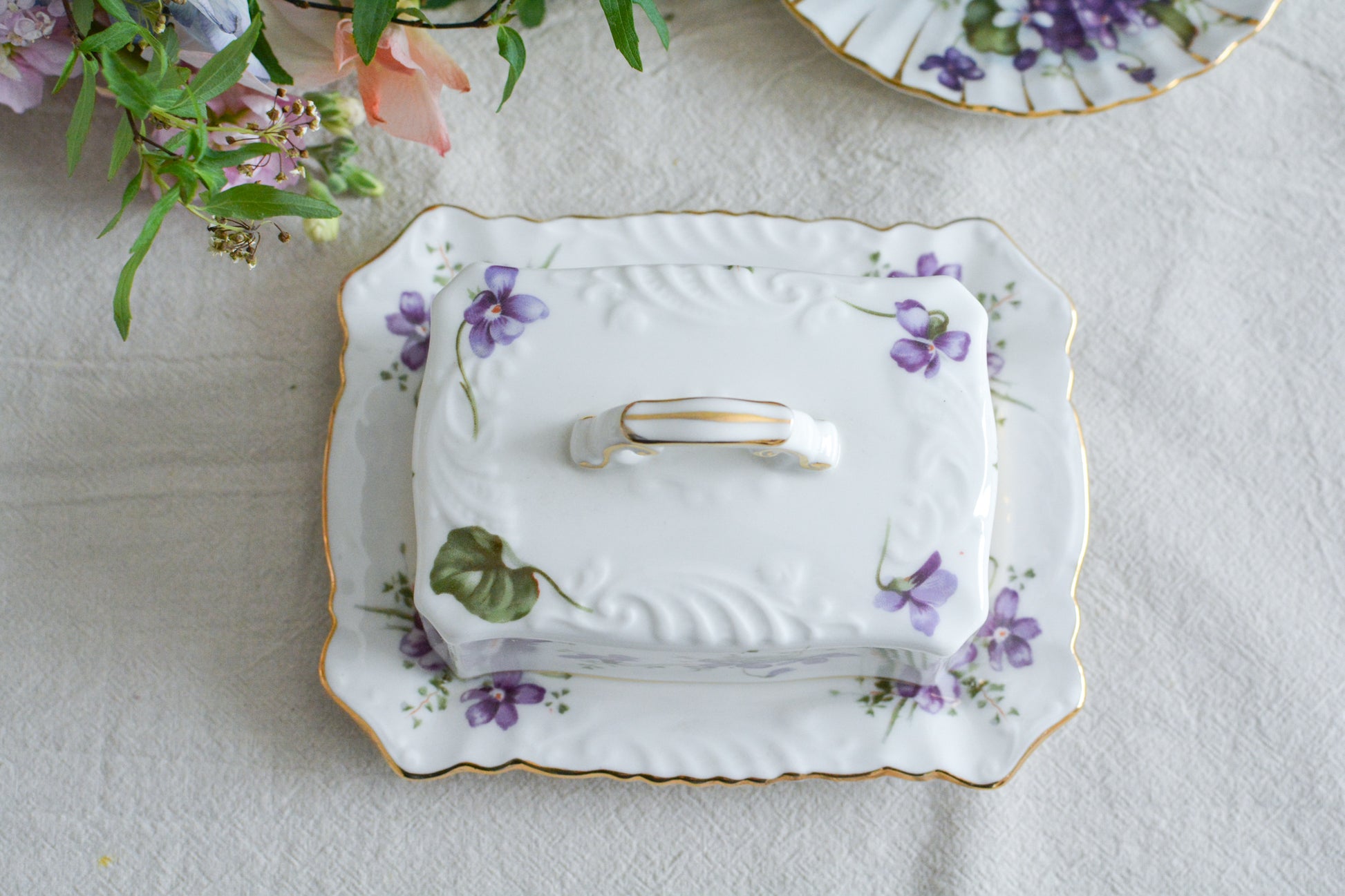 ハマースレイの人気シリーズ、ヴィクトリアンバイオレットシリーズ。珍しいバターディッシュです。お馴染みの可憐なすみれの模様が美しく、蓋の持ち手もハマースレイらしいとてもエレガントなデザイン。バターはもちろん、小さなお菓子を入れてゲストをおもてなししても素敵ですね。ティータイムを華やかに盛り上げてくれるアイテムです。