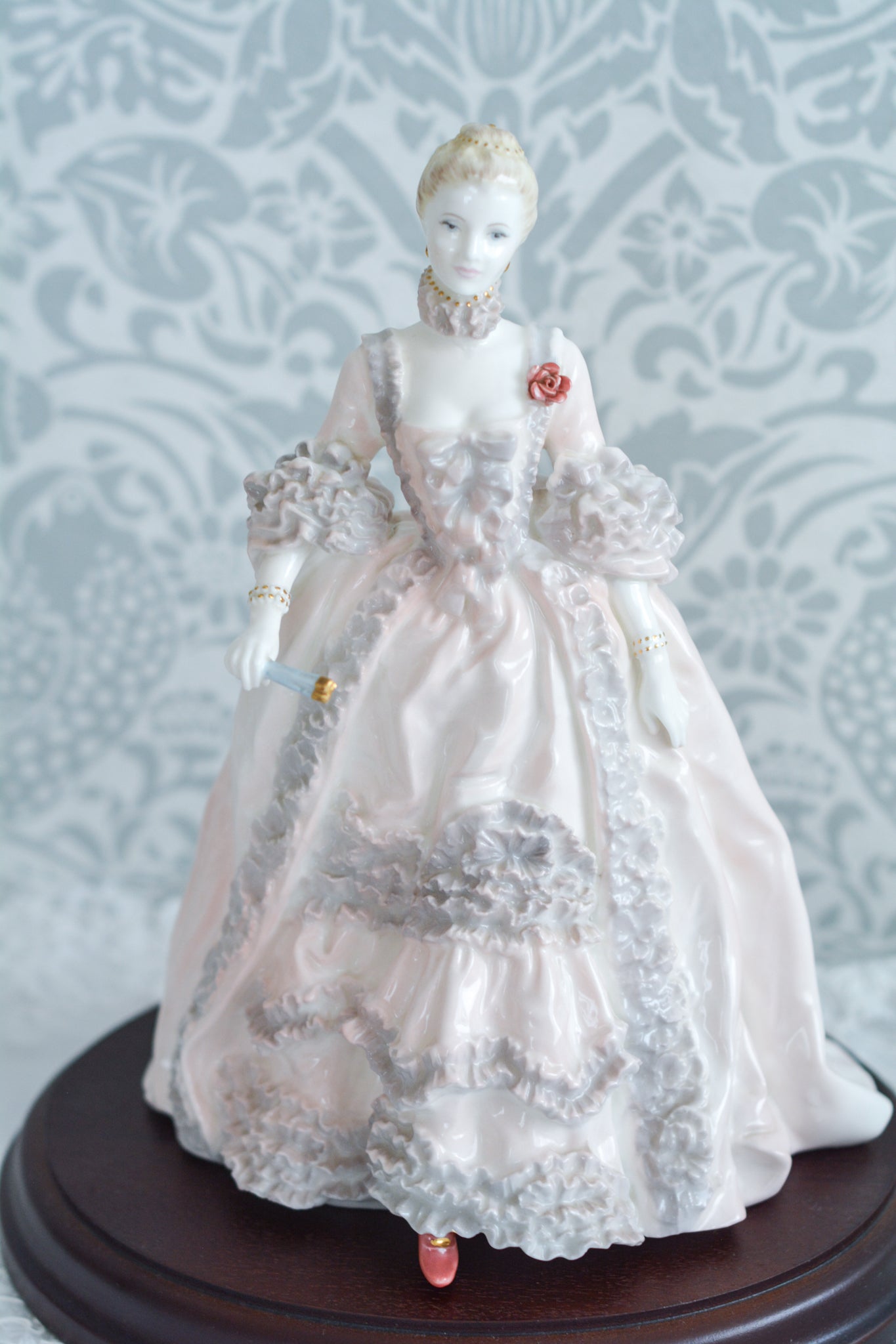 コールポートのポンパドール夫人の美しいフィギュリン。コールポートの中でも一番貴重で人気のフィギュリンではないでしょうか。美しいお顔にグレーとピンクの華やかなドレス。人気があるのも分かります。ポンパドール夫人はその美顔からフランスルイ15世の公式の愛妾となったのは有名な話。美顔だけでなく、頭もとてもよく政治にも積極的に関与しています。色々な側面を持ち合わせますが、芸術を愛し、その発展に大きな影響を与えました。ポンパドール夫人の時代はフランスを中心に優美なロココ様式が流行します。イギリスで1810年〜1830年代頃に流行したロココリバイバルはフランスのロココ様式の影響を受けてイギリスでロココ様式が再流行したものです。そんなポンパドール夫人のフィギュリンは、キャビネットに飾ってもティータイムにテーブルに置いてもどんなシーンでも、パッとスポットライトが当たったかのような存在感です。