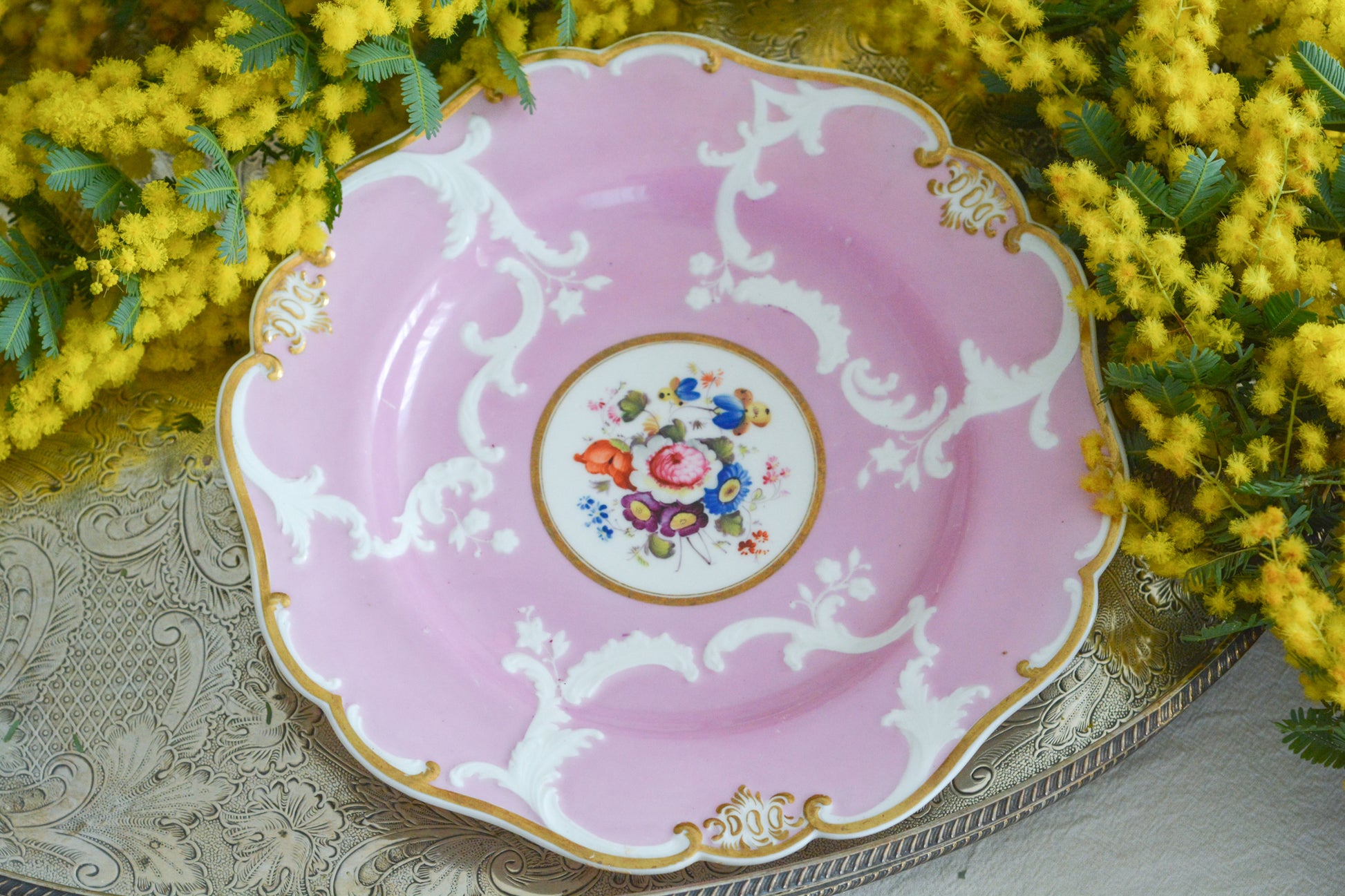 可愛らしいピンクカラーに中央にハンドペイントで丁寧に描かれたブーケの模様が美しいプレートです。エンボスの模様も優雅でチョコレートや小さな焼き菓子、パンどんなものを盛り付けても品よくまとまりそうです。一ヶ所小さなヘアラインがあるためお値打ち価格になっています。