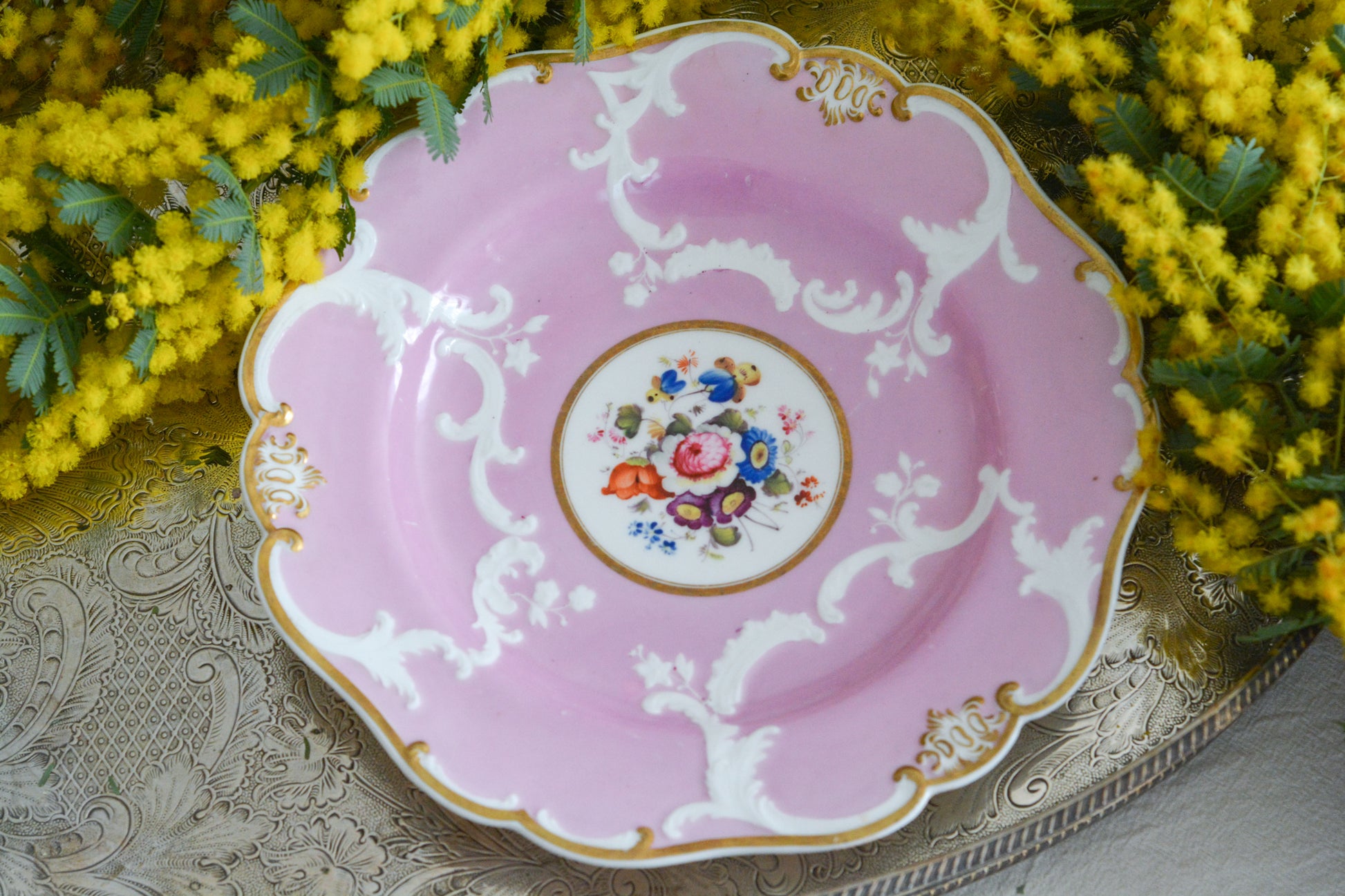 可愛らしいピンクカラーに中央にハンドペイントで丁寧に描かれたブーケの模様が美しいプレートです。エンボスの模様も優雅でチョコレートや小さな焼き菓子、パンどんなものを盛り付けても品よくまとまりそうです。一ヶ所小さなヘアラインがあるためお値打ち価格になっています。