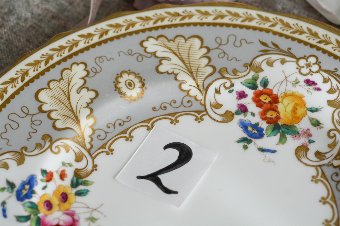 コウルドンのティファニーパターンの素敵なデザートプレートです。ハロッズがオーダーしたもので、ティファニーのスタンプはありませんが、柄はティファニーがコウルドンに特注したパターンです。ティファニーらしい上品な絵柄がとても美しくでコウルドンの中でも人気のシリーズです。当時も人気があったのでしょう。いろいろな小売店がこのパターンをオーダーしています。グレーカラーは柔らかい雰囲気で金彩との相性もいいです。とてもエレガントなプレートです。