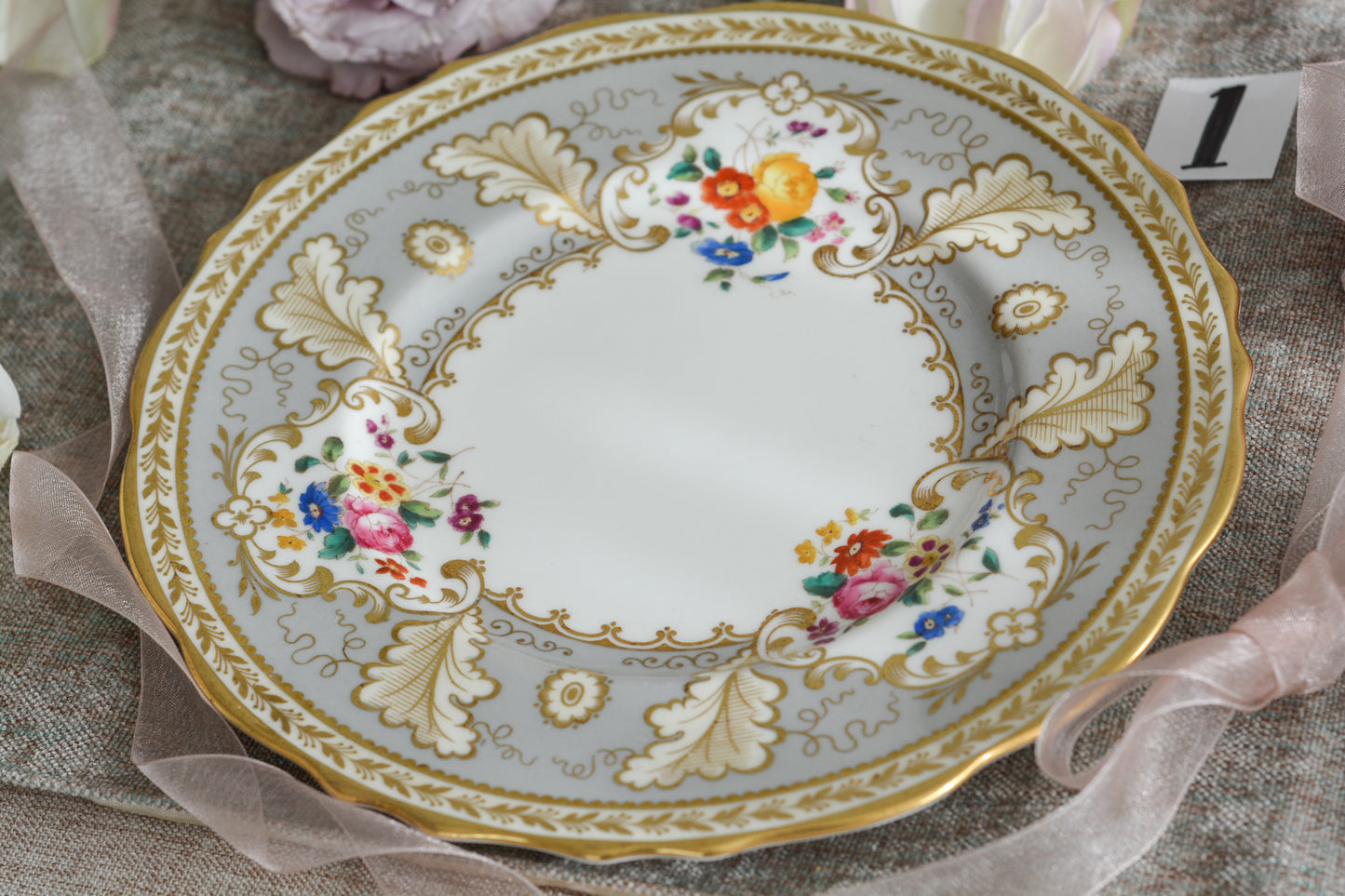 コウルドンのティファニーパターンの素敵なデザートプレートです。ハロッズがオーダーしたもので、ティファニーのスタンプはありませんが、柄はティファニーがコウルドンに特注したパターンです。ティファニーらしい上品な絵柄がとても美しくでコウルドンの中でも人気のシリーズです。当時も人気があったのでしょう。いろいろな小売店がこのパターンをオーダーしています。グレーカラーは柔らかい雰囲気で金彩との相性もいいです。とてもエレガントなプレートです。