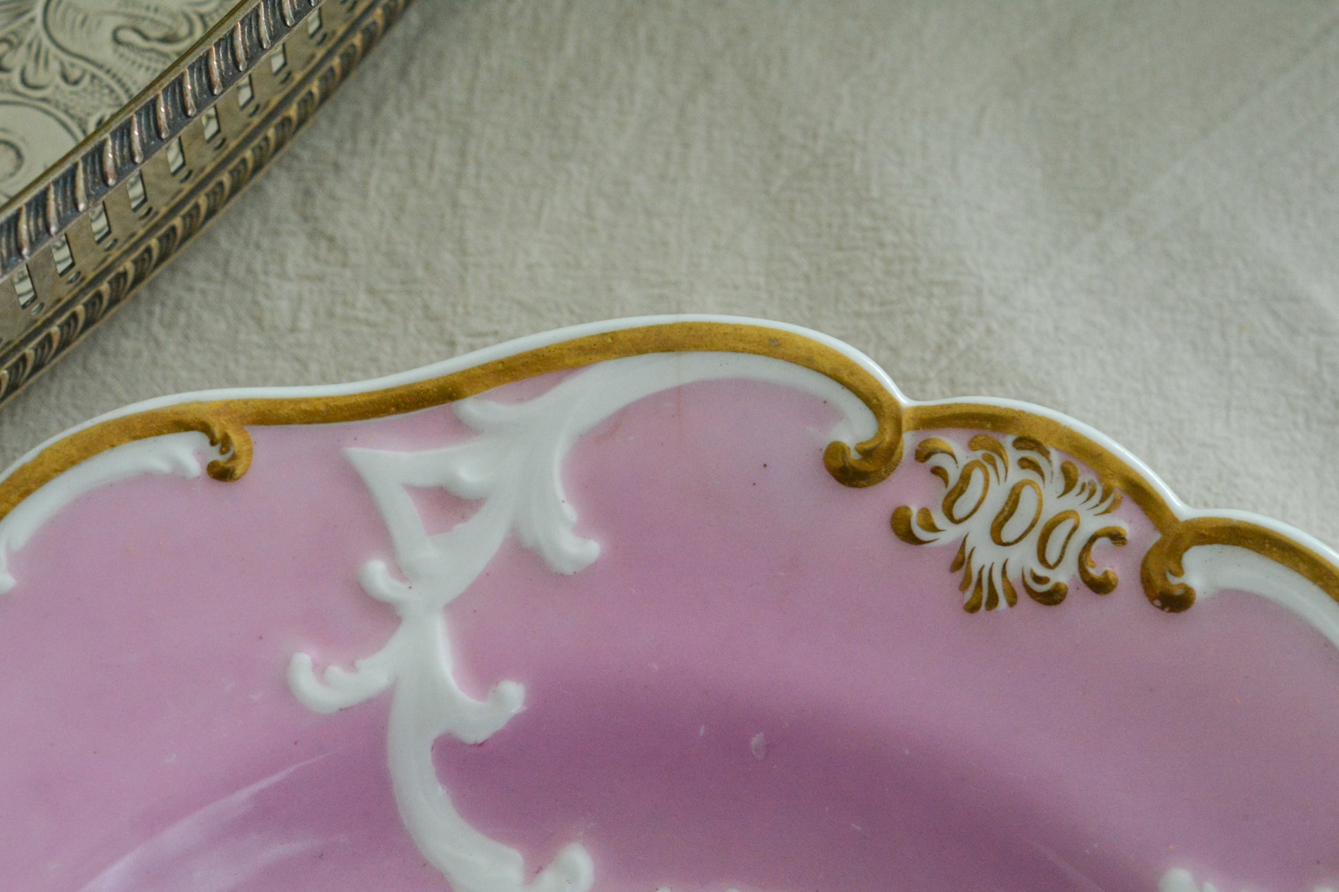 可愛らしいピンクカラーに中央にハンドペイントで丁寧に描かれたブーケの模様が美しいプレートです。エンボスの模様も優雅でチョコレートや小さな焼き菓子、パンどんなものを盛り付けても品よくまとまりそうです。一ヶ所小さなヘアラインがあるためお値打ち価格になっています。