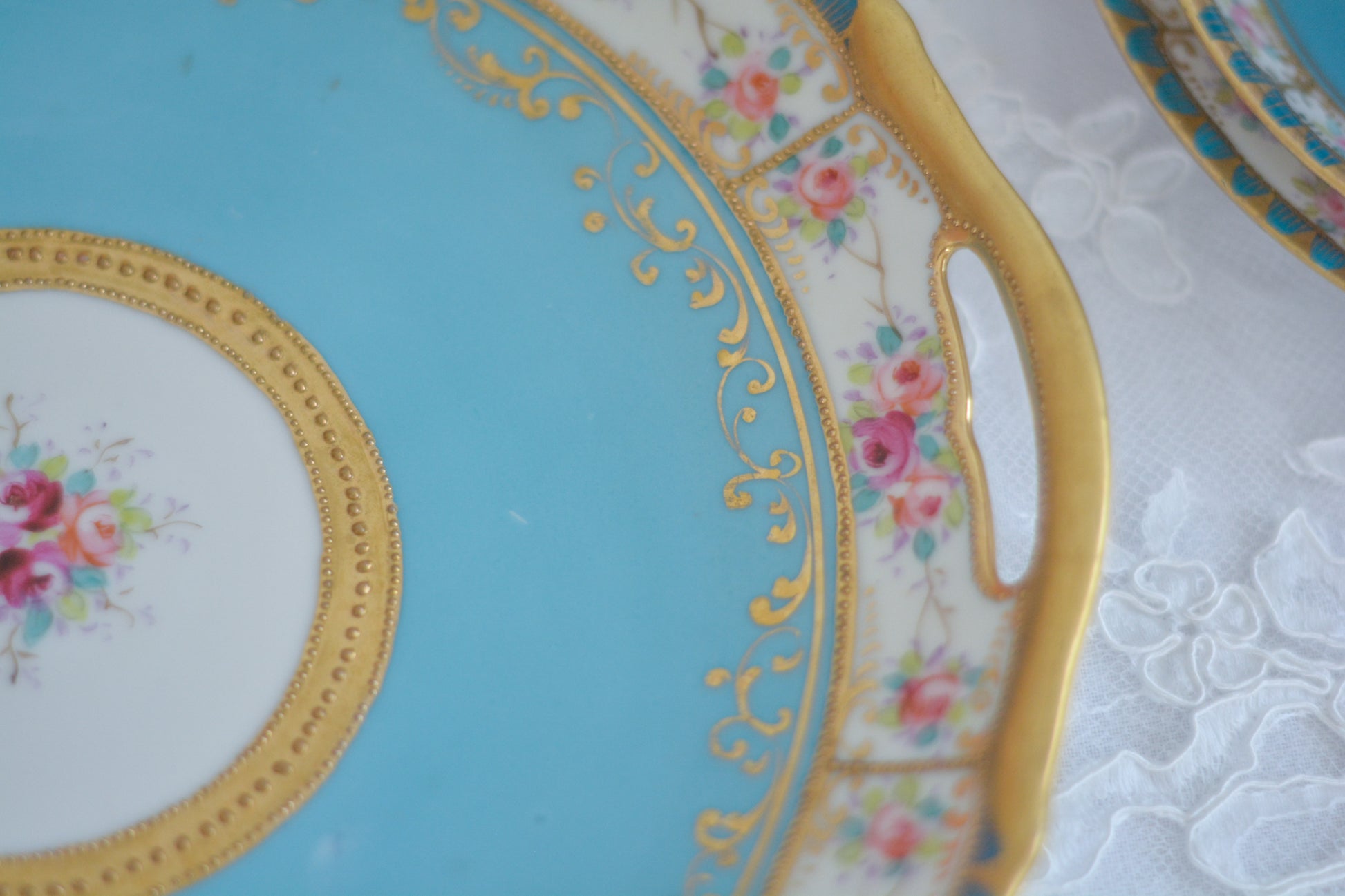 L&COという日本のメーカーのアンティーク里帰り品です。美しいターコイズブルーに金盛りの金彩、ハンドペイントで描かれた可憐なバラが上品なお品。1800年代後半頃からノリタケをはじめ日本からたくさんのメーカーが英国やアメリカに陶磁器を輸出していました。L&COは英国の老舗デパートリバティで販売されていたと言われています。キラキラしたティーセットやプレート達がデパートに並べられている風景は、当時の人々の目と心を楽しませていたことでしょう。