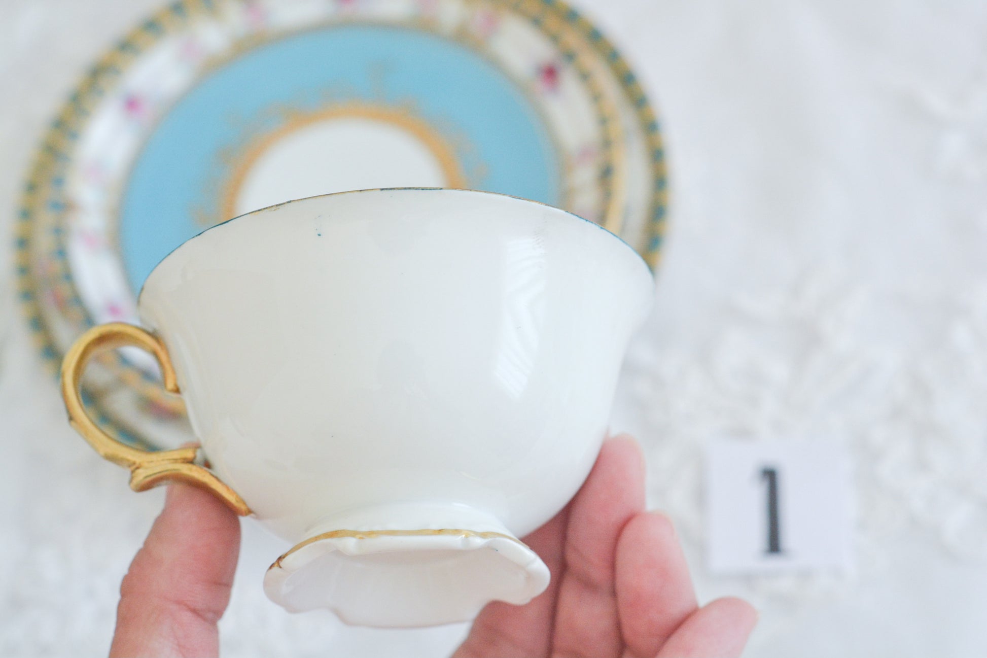 L&COという日本のメーカーのアンティーク里帰り品です。美しいターコイズブルーに金盛りの金彩、ハンドペイントで描かれた可憐なバラが上品なお品。1800年代後半頃からノリタケをはじめ日本からたくさんのメーカーが英国やアメリカに陶磁器を輸出していました。L&COは英国の老舗デパートリバティで販売されていたと言われています。キラキラしたティーセットがデパートに並べられている風景は、当時の人々の目と心を楽しませていたことでしょう。オールドニッポンの美しいティーカップでティータイムをお楽しみください。