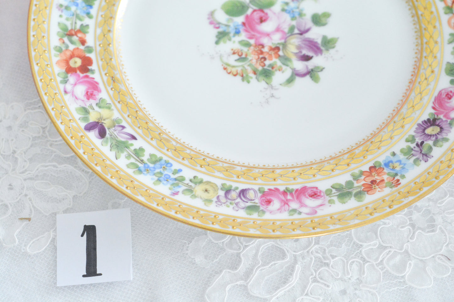 こちらのプレート達はドレスデンの工房で作られてはいますが、カール・ティーメ工房の作品ではありません。特に美しいので特集コーナーに入れさせていただきました。ハンドペイントで描かれた美しい花々に金彩の葉っぱの模様のような縁取りが豪華なお品。金盛りのドットがより花を添えています。キャビネットプレートとしても実際にお使いいただいても素敵なお品です。バックスタンプは1883年〜1893年頃に使われていた王冠マークで、いくつかの工房が集まって使用していました。バックスタンの上には金彩でお花が描かれています。