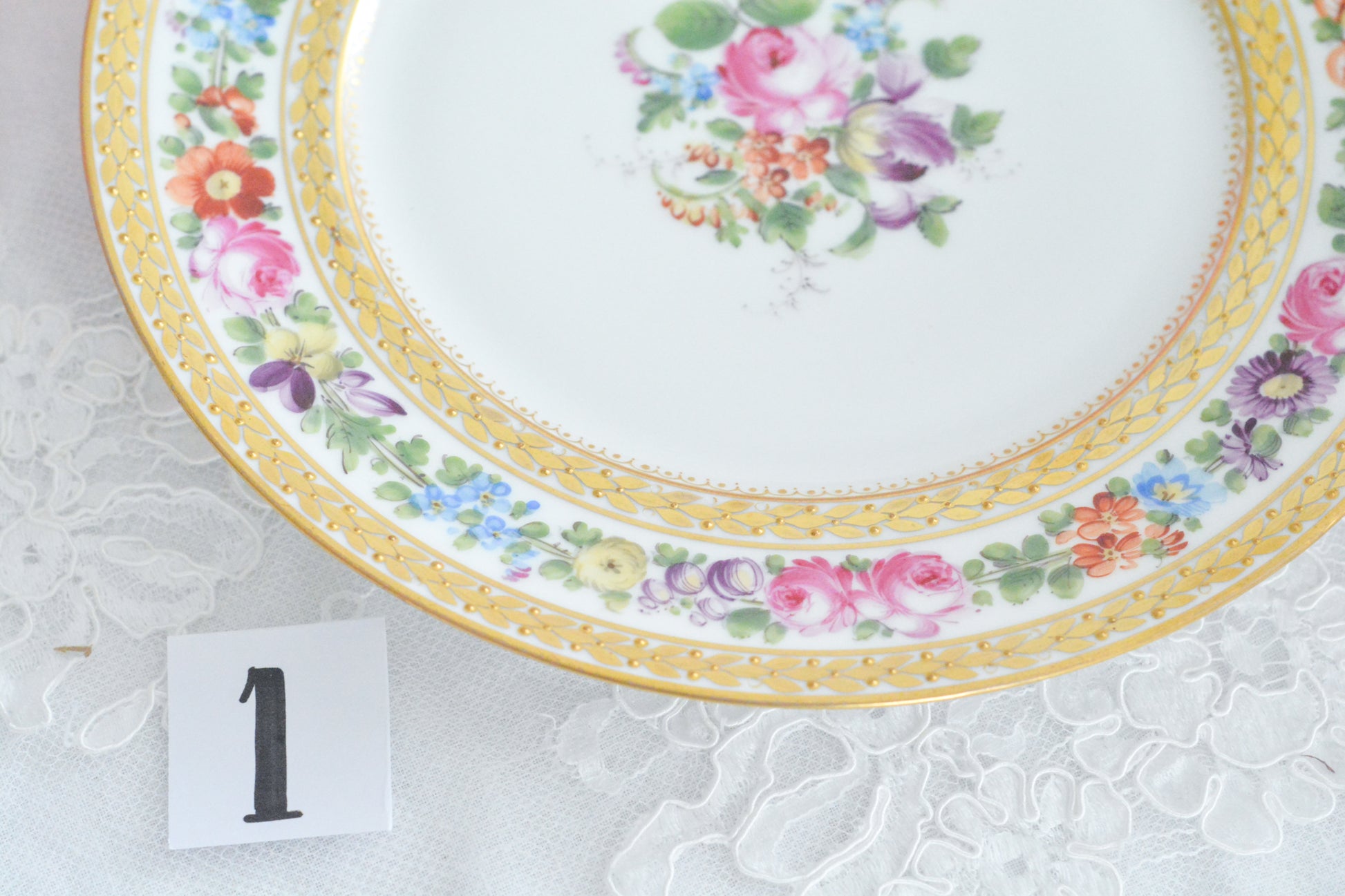 こちらのプレート達はドレスデンの工房で作られてはいますが、カール・ティーメ工房の作品ではありません。特に美しいので特集コーナーに入れさせていただきました。ハンドペイントで描かれた美しい花々に金彩の葉っぱの模様のような縁取りが豪華なお品。金盛りのドットがより花を添えています。キャビネットプレートとしても実際にお使いいただいても素敵なお品です。バックスタンプは1883年〜1893年頃に使われていた王冠マークで、いくつかの工房が集まって使用していました。バックスタンの上には金彩でお花が描かれています。