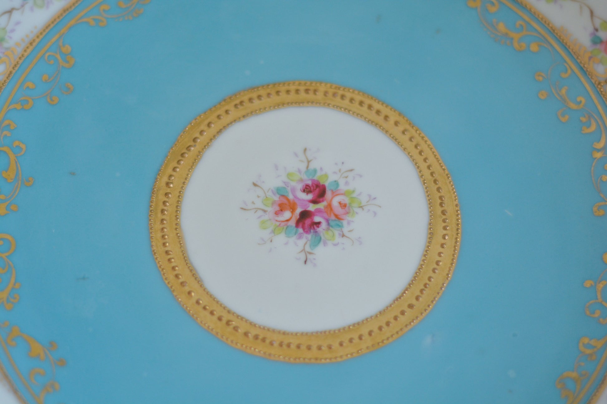 L&COという日本のメーカーのアンティーク里帰り品です。美しいターコイズブルーに金盛りの金彩、ハンドペイントで描かれた可憐なバラが上品なお品。1800年代後半頃からノリタケをはじめ日本からたくさんのメーカーが英国やアメリカに陶磁器を輸出していました。L&COは英国の老舗デパートリバティで販売されていたと言われています。キラキラしたティーセットやプレート達がデパートに並べられている風景は、当時の人々の目と心を楽しませていたことでしょう。