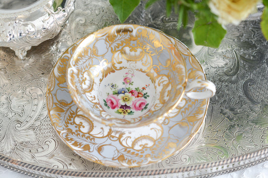 ハンドペイントで描かれた花々に金彩の模様がとても美しい、優美なシェイプのカップ&ソーサー。同じパターンのお品をいくつかのメーカーで見たことがありますが、残念ながらどのメーカーか判断がつきませんでした。カップとソーサーの中央に描かれた花々はとても繊細なタッチで丁寧に描かれています。グレーカラーと金彩の組み合わせは優しい印象ですね。テーブルを優しく華やかに演出してくれます。