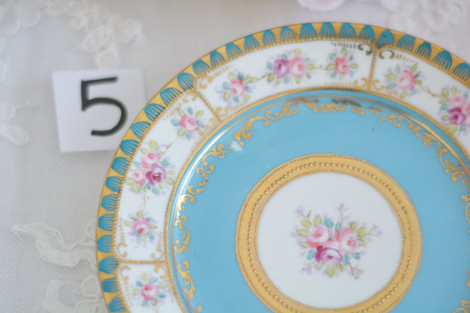 L&COという日本のメーカーのアンティーク里帰り品です。美しいターコイズブルーに金盛りの金彩、ハンドペイントで描かれた可憐なバラが上品なお品。1800年代後半頃からノリタケをはじめ日本からたくさんのメーカーが英国やアメリカに陶磁器を輸出していました。L&COは英国の老舗デパートリバティで販売されていたと言われています。キラキラしたティーセットがデパートに並べられている風景は、当時の人々の目と心を楽しませていたことでしょう。オールドニッポンの美しいティーカップでティータイムをお楽しみください。