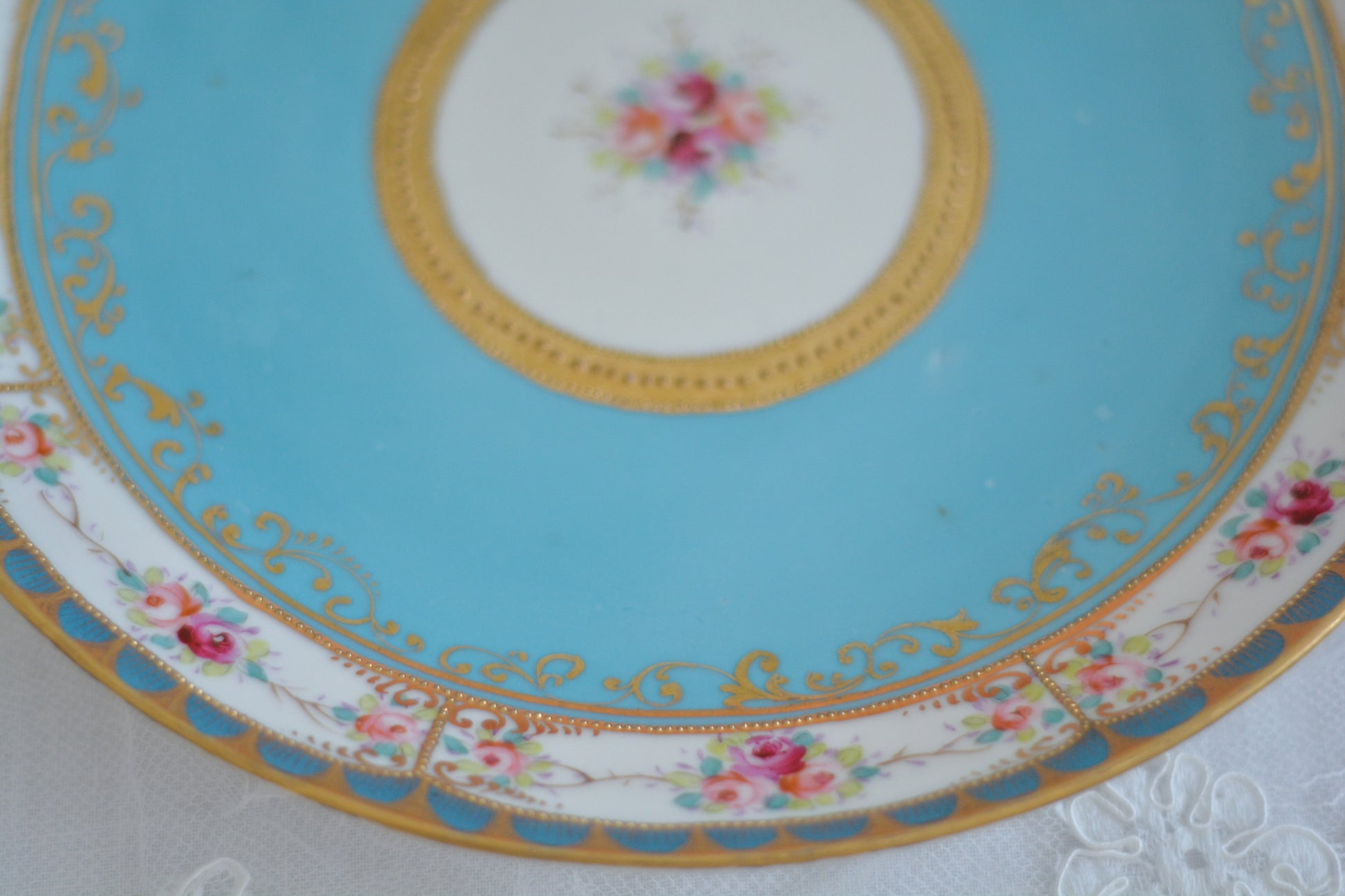 L&COという日本のメーカーのアンティーク里帰り品です。美しいターコイズブルーに金盛りの金彩、ハンドペイントで描かれた可憐なバラが上品なお品。1800年代後半頃からノリタケをはじめ日本からたくさんのメーカーが英国やアメリカに陶磁器を輸出していました。L&COは英国の老舗デパートリバティで販売されていたと言われています。キラキラしたティーセットやプレート達がデパートに並べられている風景は、当時の人々の目と心を楽しませていたことでしょう。