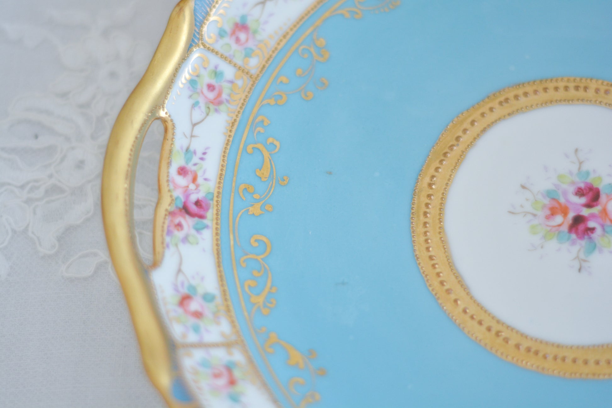 L&COという日本のメーカーのアンティーク里帰り品です。美しいターコイズブルーに金盛りの金彩、ハンドペイントで描かれた可憐なバラが上品なお品。1800年代後半頃からノリタケをはじめ日本からたくさんのメーカーが英国やアメリカに陶磁器を輸出していました。L&COは英国の老舗デパートリバティで販売されていたと言われています。キラキラしたティーセットやプレート達がデパートに並べられている風景は、当時の人々の目と心を楽しませていたことでしょう。