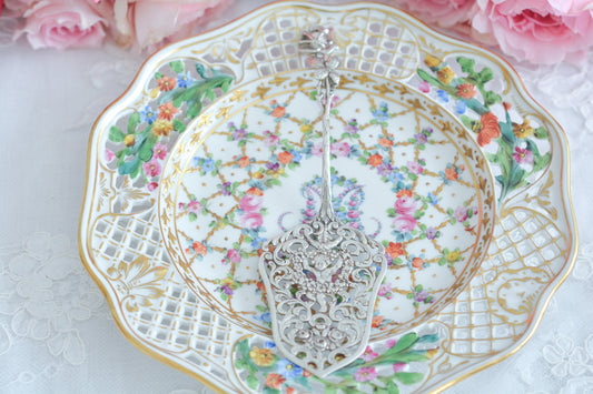 ドイツ クリストフウィドマンのとっても愛らしいパティスリーサーバーです。  クリストウィドマンは1919年に創業した銀器メーカーです。高い技術を持った職人さん達の作る繊細で美しい銀器に魅了されたたくさんのコレクターさん達に愛されています。 特に美しいヒルデスハイムローズのシリーズは人気がとても高いです。  こちらもガーランドを持った天使の透かし模様とヒルデスハイムローズの持ち手が大変美しいサーバーで、まるで芸術品のようです。