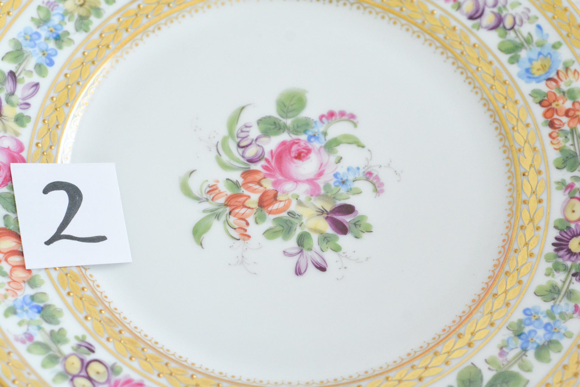 こちらのプレート達はドレスデンの工房で作られてはいますが、カール・ティーメ工房の作品ではありません。特に美しいので特集コーナーに入れさせていただきました。ハンドペイントで描かれた美しい花々に金彩の葉っぱの模様のような縁取りが豪華なお品。金盛りのドットがより花を添えています。キャビネットプレートとしても実際にお使いいただいても素敵なお品です。バックスタンプは1883年〜1893年頃に使われていた王冠マークで、いくつかの工房が集まって使用していました。バックスタンの上には金彩でお花が描かれています。