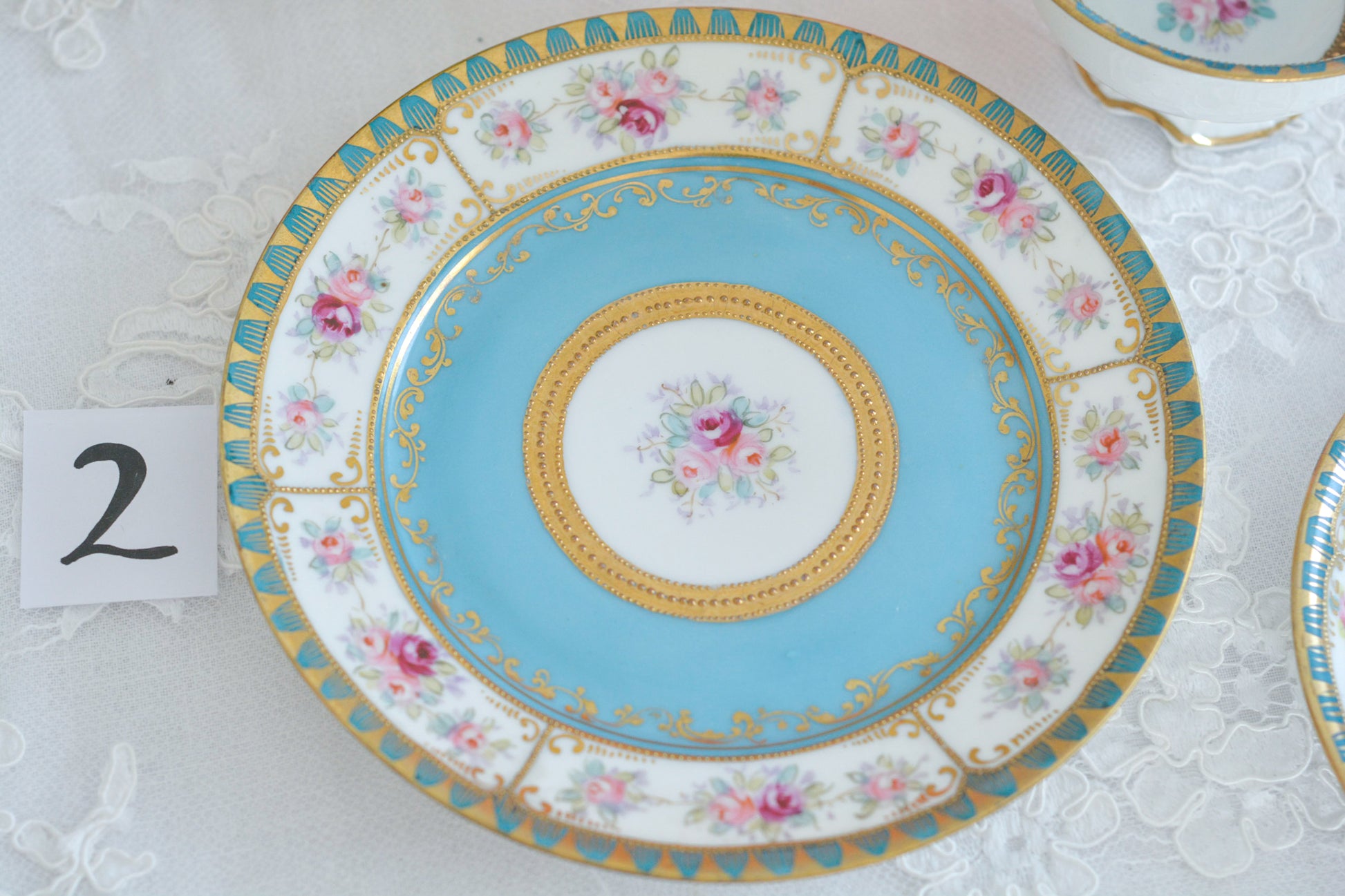 L&COという日本のメーカーのアンティーク里帰り品です。美しいターコイズブルーに金盛りの金彩、ハンドペイントで描かれた可憐なバラが上品なお品。1800年代後半頃からノリタケをはじめ日本からたくさんのメーカーが英国やアメリカに陶磁器を輸出していました。L&COは英国の老舗デパートリバティで販売されていたと言われています。キラキラしたティーセットがデパートに並べられている風景は、当時の人々の目と心を楽しませていたことでしょう。オールドニッポンの美しいティーカップでティータイムをお楽しみください。