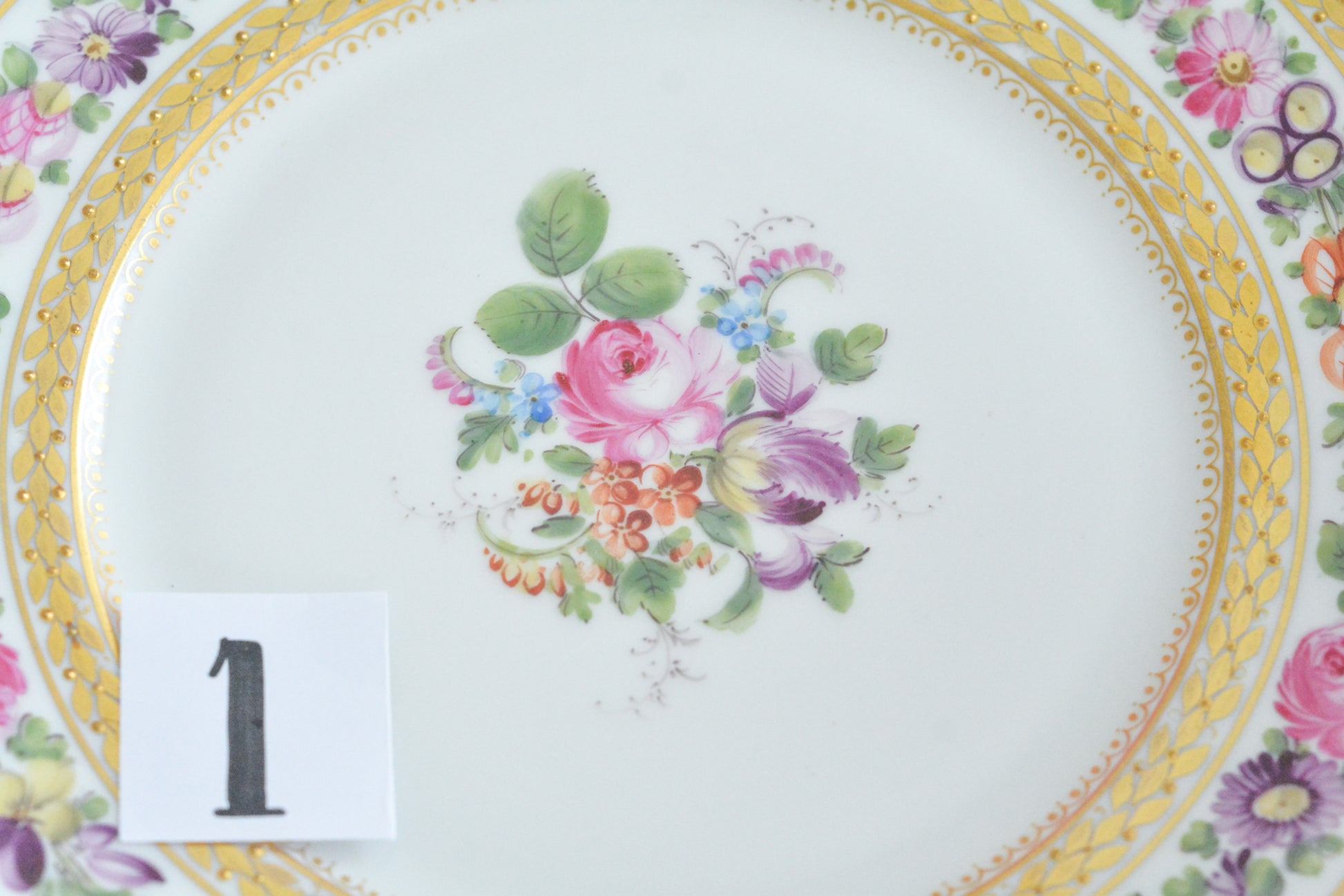 こちらのプレート達はドレスデンの工房で作られてはいますが、カール・ティーメ工房の作品ではありません。特に美しいので特集コーナーに入れさせていただきました。ハンドペイントで描かれた美しい花々に金彩の葉っぱの模様のような縁取りが豪華なお品。金盛りのドットがより花を添えています。キャビネットプレートとしても実際にお使いいただいても素敵なお品です。バックスタンプは1883年〜1893年頃に使われていた王冠マークで、いくつかの工房が集まって使用していました。バックスタンの上には金彩でお花が描かれています。