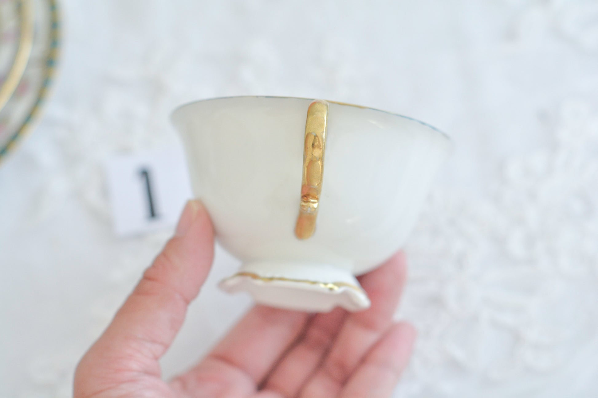 L&COという日本のメーカーのアンティーク里帰り品です。美しいターコイズブルーに金盛りの金彩、ハンドペイントで描かれた可憐なバラが上品なお品。1800年代後半頃からノリタケをはじめ日本からたくさんのメーカーが英国やアメリカに陶磁器を輸出していました。L&COは英国の老舗デパートリバティで販売されていたと言われています。キラキラしたティーセットがデパートに並べられている風景は、当時の人々の目と心を楽しませていたことでしょう。オールドニッポンの美しいティーカップでティータイムをお楽しみください。