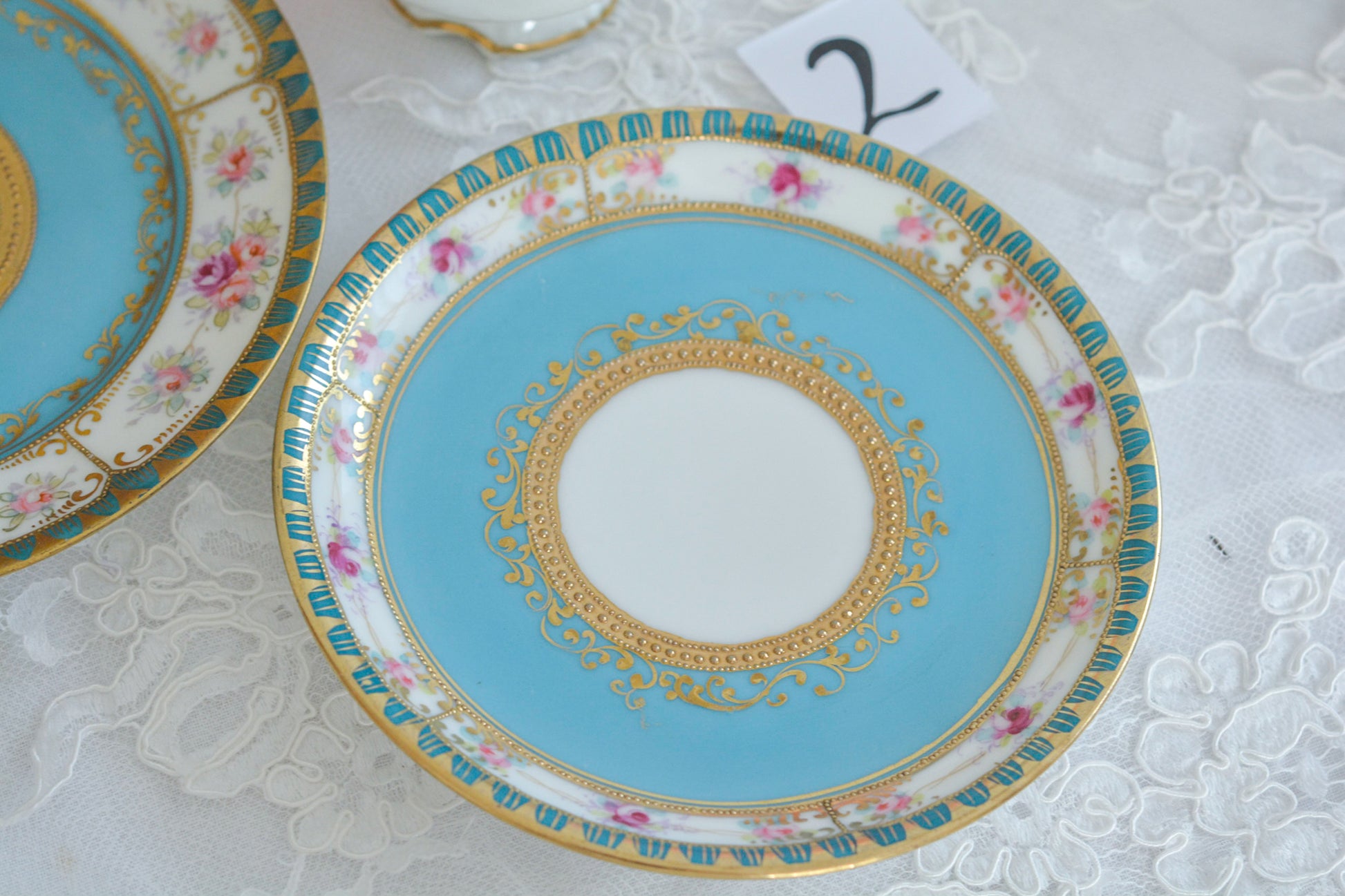 L&COという日本のメーカーのアンティーク里帰り品です。美しいターコイズブルーに金盛りの金彩、ハンドペイントで描かれた可憐なバラが上品なお品。1800年代後半頃からノリタケをはじめ日本からたくさんのメーカーが英国やアメリカに陶磁器を輸出していました。L&COは英国の老舗デパートリバティで販売されていたと言われています。キラキラしたティーセットがデパートに並べられている風景は、当時の人々の目と心を楽しませていたことでしょう。オールドニッポンの美しいティーカップでティータイムをお楽しみください。