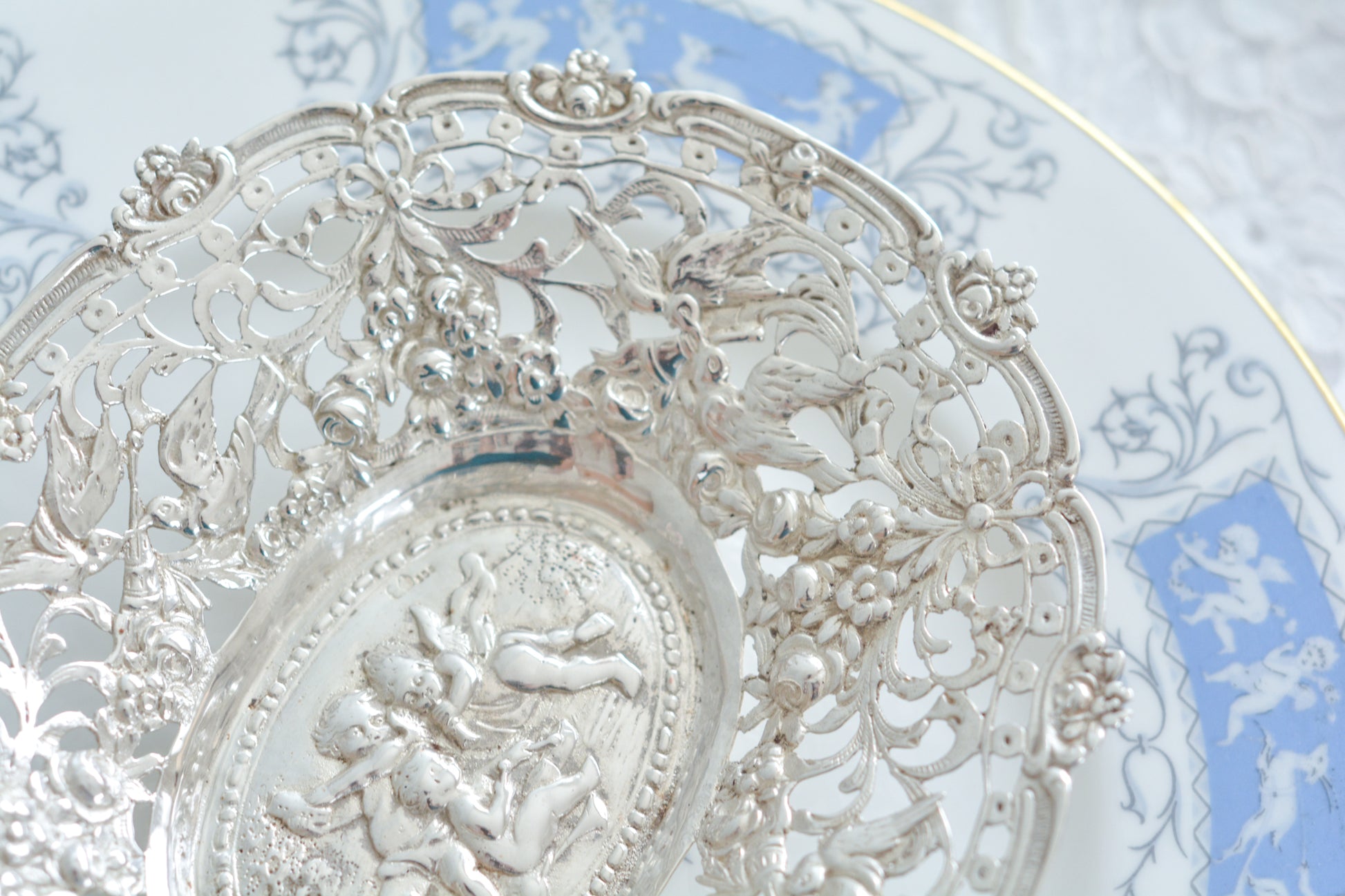 天使にリボンと薔薇のガーランドのピアス細工がとても愛らしく美しいボンボンディッシュです。 こちらはドイツで作られてイギリスに輸入されたお品です。繊細なピアス細工(透かし模様)に可愛らしい天使達がとても美しいお品です。ボンボンディッシュとはチョコレートやキャンディーなど小さなお菓子を入れて、ゲストがつまめるようにテーブルなどに置いておくためのお皿で、テーブルやお部屋に置かれていました。小ぶりなお皿で、ちょっとしたお菓子を乗せるのにぴったりです。