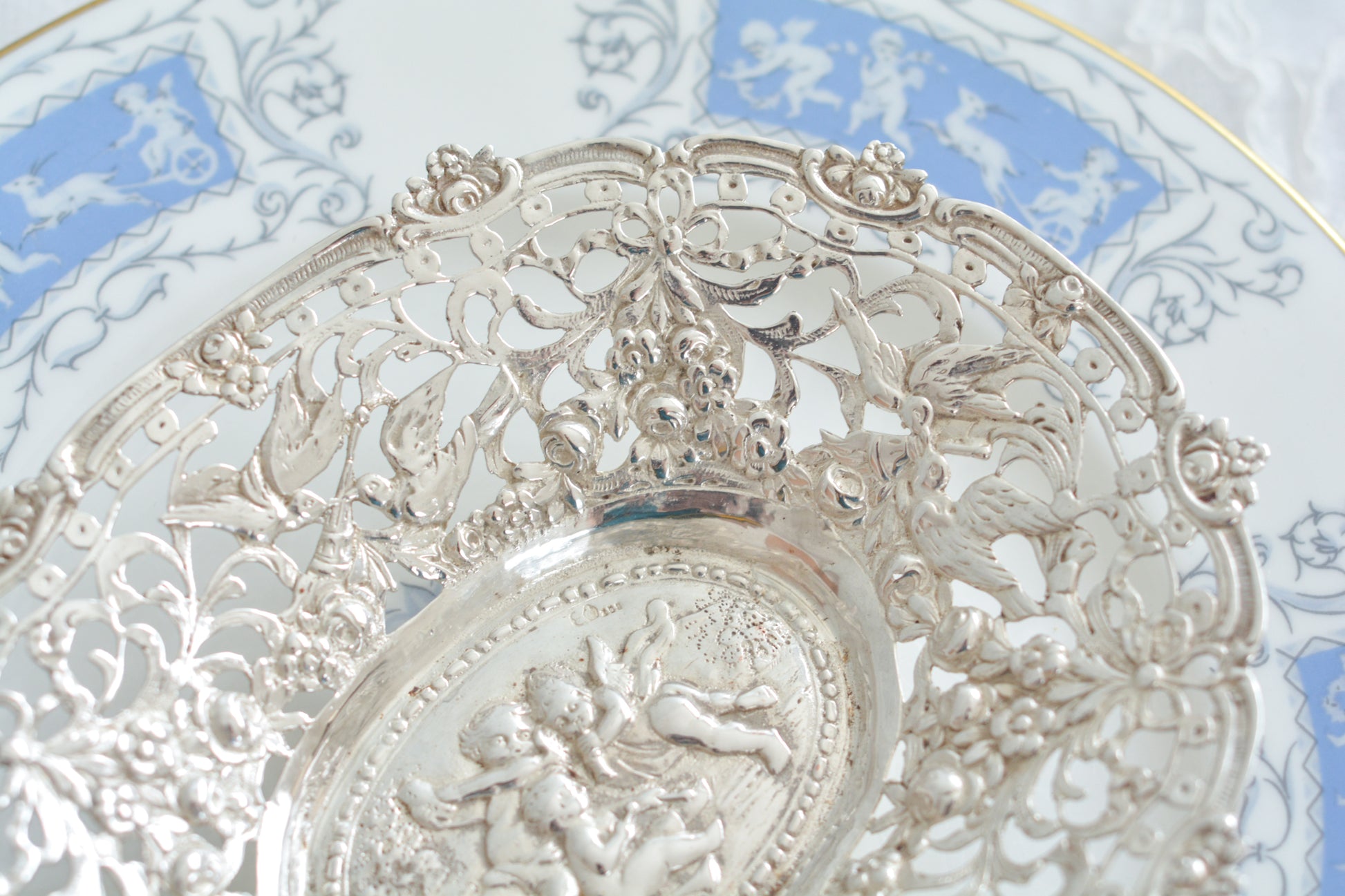 天使にリボンと薔薇のガーランドのピアス細工がとても愛らしく美しいボンボンディッシュです。 こちらはドイツで作られてイギリスに輸入されたお品です。繊細なピアス細工(透かし模様)に可愛らしい天使達がとても美しいお品です。ボンボンディッシュとはチョコレートやキャンディーなど小さなお菓子を入れて、ゲストがつまめるようにテーブルなどに置いておくためのお皿で、テーブルやお部屋に置かれていました。小ぶりなお皿で、ちょっとしたお菓子を乗せるのにぴったりです。