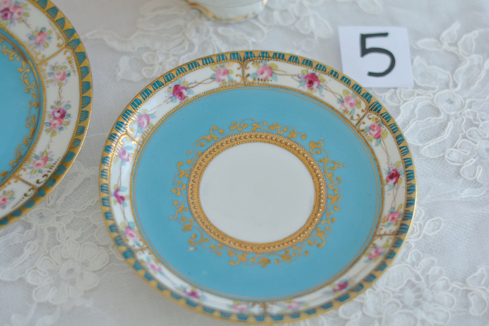 L&COという日本のメーカーのアンティーク里帰り品です。美しいターコイズブルーに金盛りの金彩、ハンドペイントで描かれた可憐なバラが上品なお品。1800年代後半頃からノリタケをはじめ日本からたくさんのメーカーが英国やアメリカに陶磁器を輸出していました。L&COは英国の老舗デパートリバティで販売されていたと言われています。キラキラしたティーセットがデパートに並べられている風景は、当時の人々の目と心を楽しませていたことでしょう。オールドニッポンの美しいティーカップでティータイムをお楽しみください。