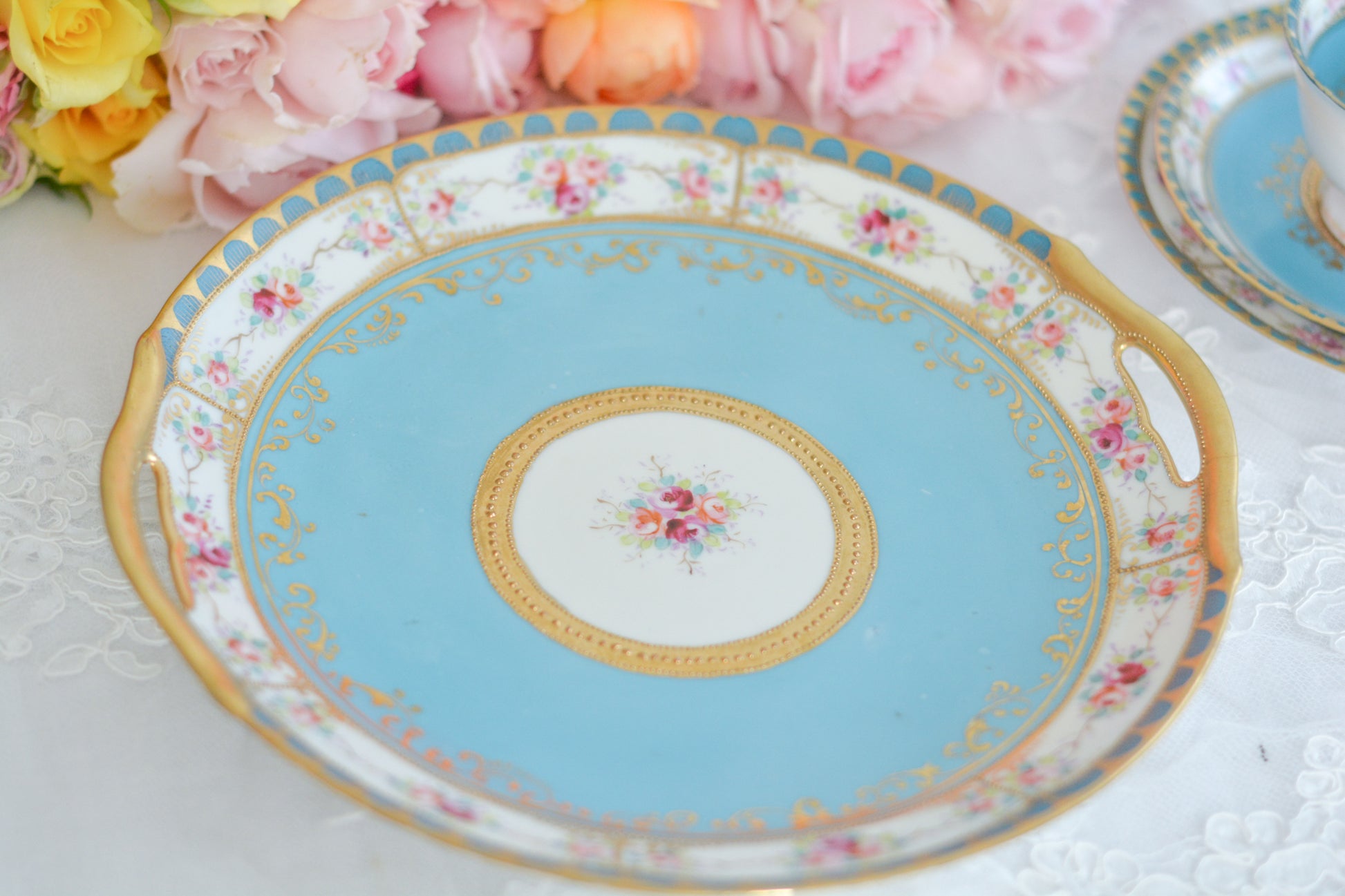 L&COという日本のメーカーのアンティーク里帰り品です。美しいターコイズブルーに金盛りの金彩、ハンドペイントで描かれた可憐なバラが上品なお品。1800年代後半頃からノリタケをはじめ日本からたくさんのメーカーが英国やアメリカに陶磁器を輸出していました。L&COは英国の老舗デパートリバティで販売されていたと言われています。キラキラしたティーセットやプレート達がデパートに並べられている風景は、当時の人々の目と心を楽しませていたことでしょう。