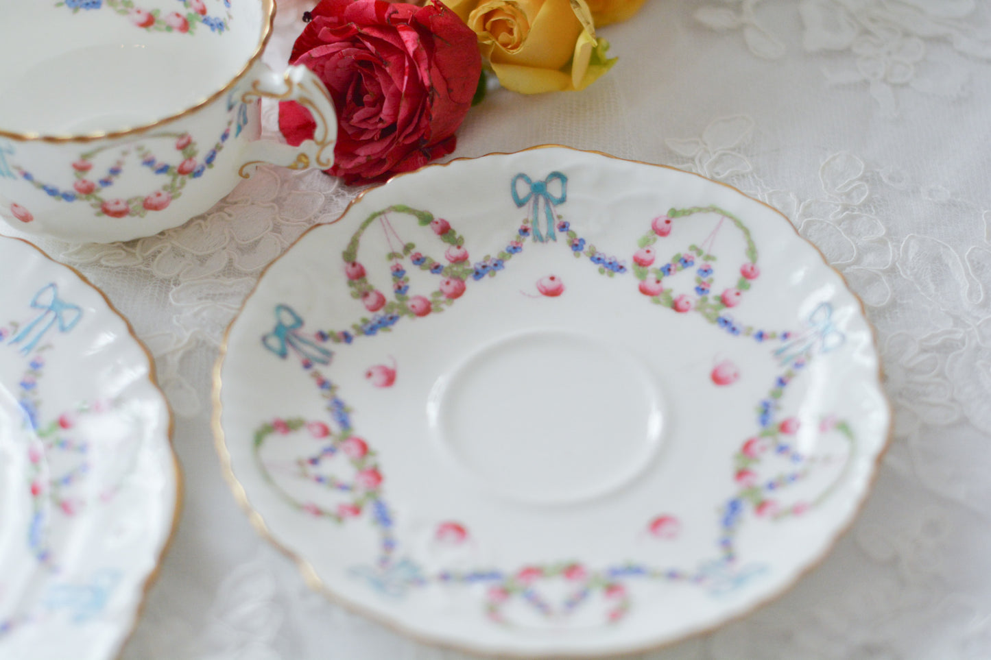 英国アンティーク、ハマースレイの貴重なハンドペイントのティートリオです。ブルーのリボンに薔薇と忘れな草のガーランドがとても可愛らしいです。