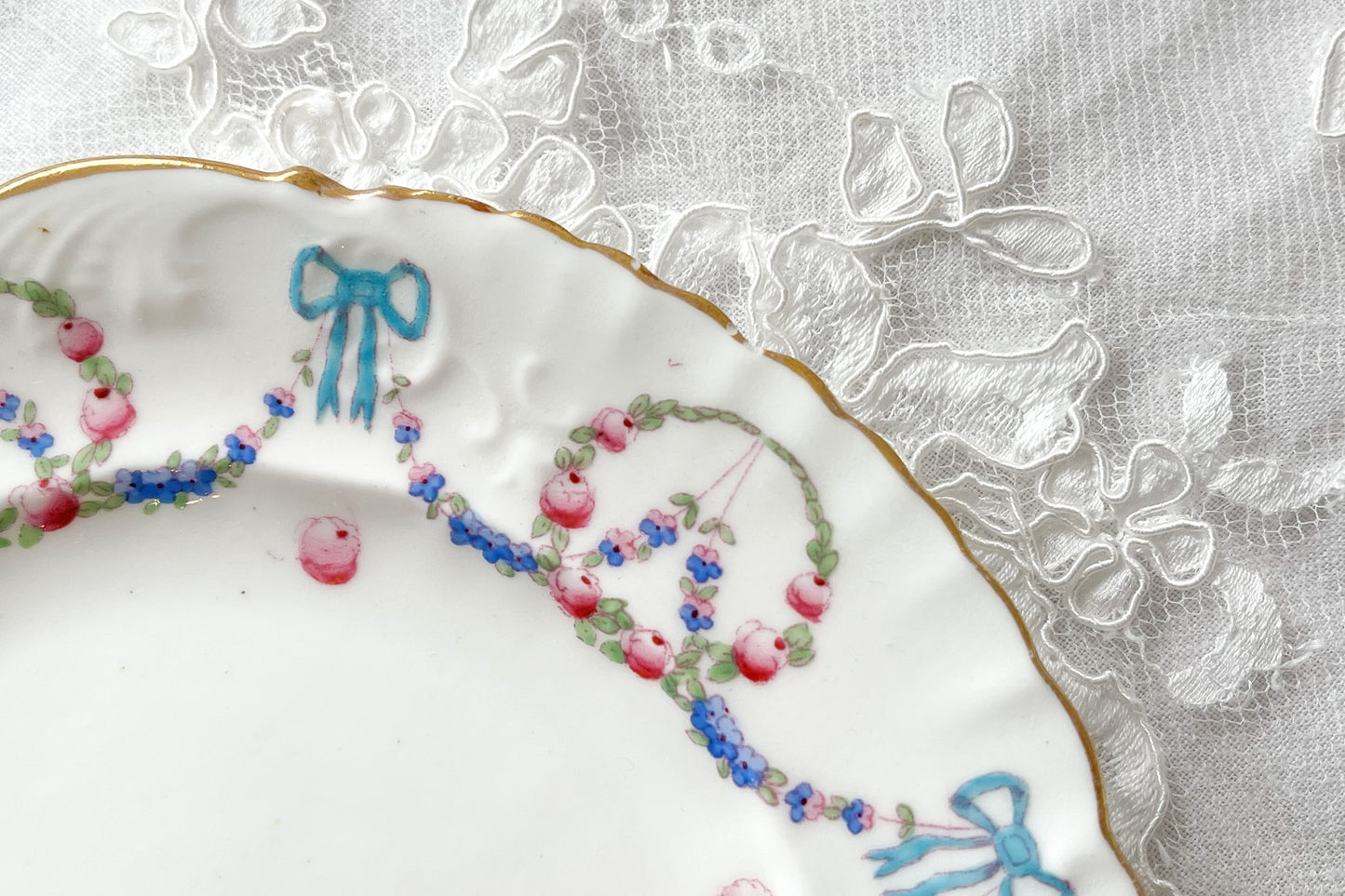 英国アンティーク、ハマースレイの貴重なハンドペイントのティートリオです。ブルーのリボンに薔薇と忘れな草のガーランドがとても可愛らしいです。