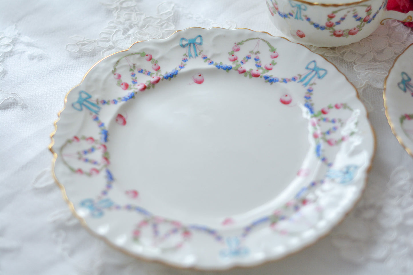 英国アンティーク、ハマースレイの貴重なハンドペイントのティートリオです。ブルーのリボンに薔薇と忘れな草のガーランドがとても可愛らしいです。