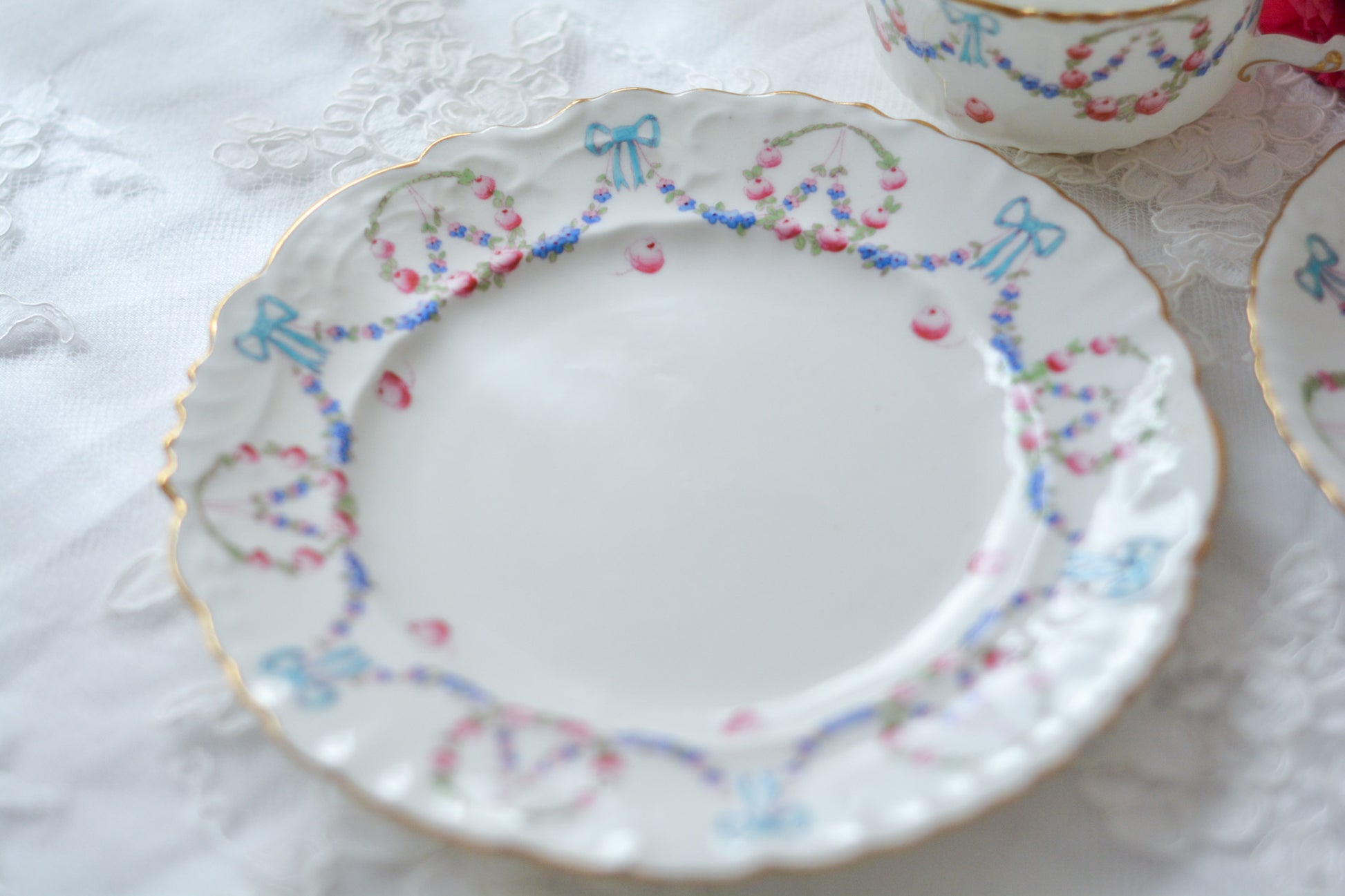 英国アンティーク、ハマースレイの貴重なハンドペイントのティートリオです。ブルーのリボンに薔薇と忘れな草のガーランドがとても可愛らしいです。