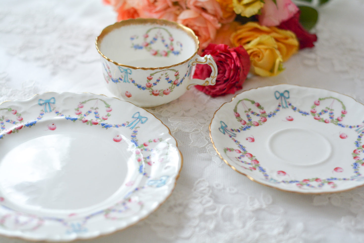 英国アンティーク、ハマースレイの貴重なハンドペイントのティートリオです。ブルーのリボンに薔薇と忘れな草のガーランドがとても可愛らしいです。