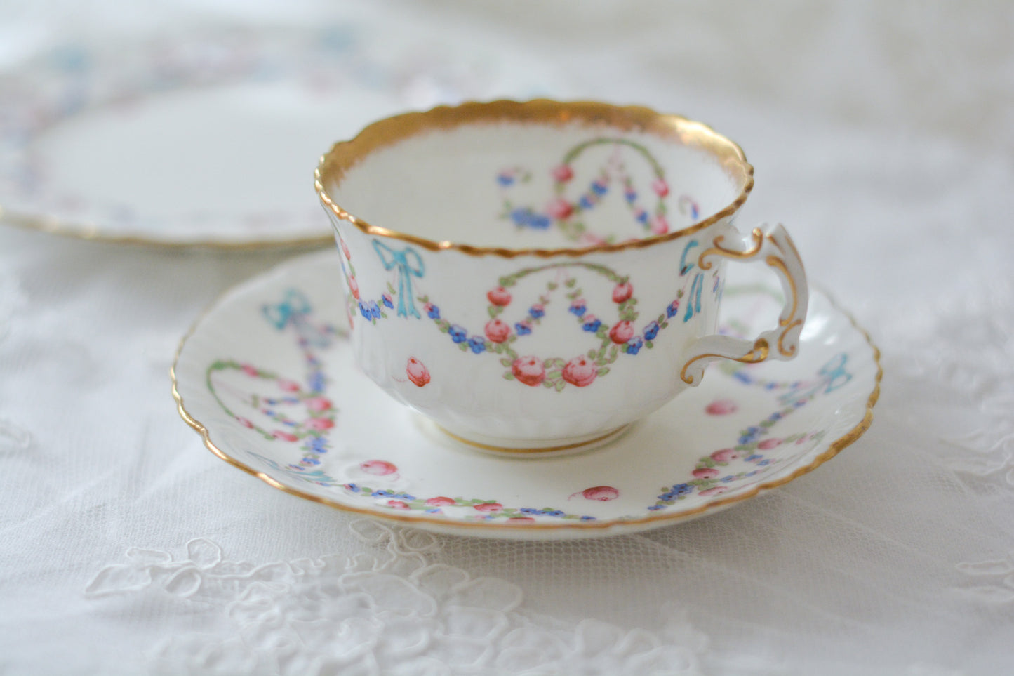 英国アンティーク、ハマースレイの貴重なハンドペイントのティートリオです。ブルーのリボンに薔薇と忘れな草のガーランドがとても可愛らしいです。