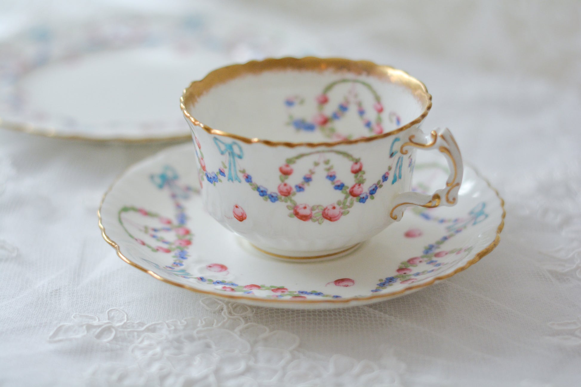 英国アンティーク、ハマースレイの貴重なハンドペイントのティートリオです。ブルーのリボンに薔薇と忘れな草のガーランドがとても可愛らしいです。