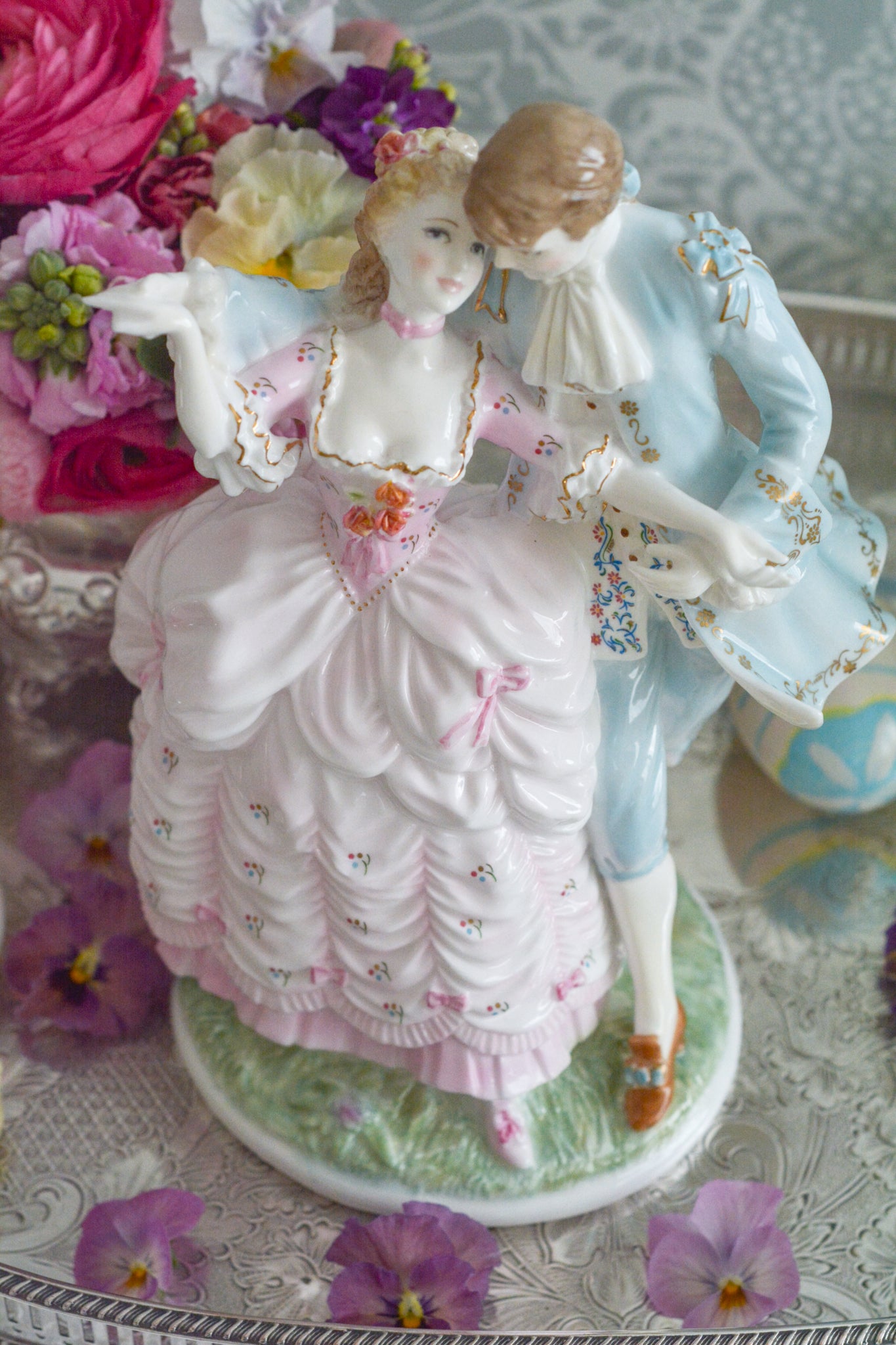 ロイヤルウースターの「AGE  OF CORTSHIP」シリーズの「The Flirtation」というフィギュリンです。「The Flirtation」「The Tryst」「The Betrothal」「The Proposal」があり、シリーズ名の通り、男女ペアのフィギュリンで構成されています。 寄り添ってダンスしているようにも見えます。 そしてパステルカラーの衣装の雰囲気やお顔の表情も柔らかく、初々しい様子も伝わってきます。2500体しか製造されていない大変貴重なフィギュリンです。