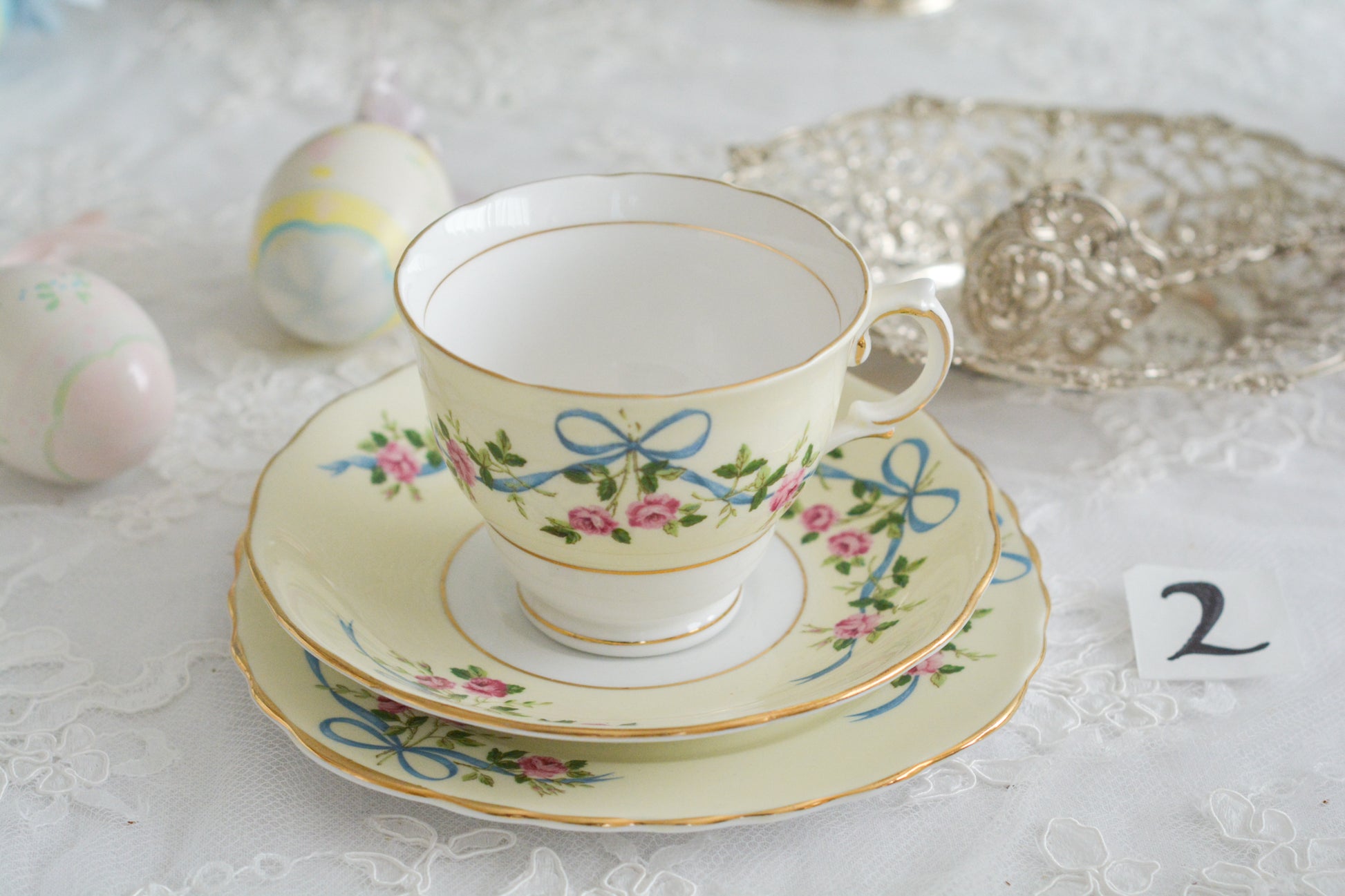 コルクラフ(Colclough)の可愛らしいティートリオ。コルクラフは1890年にハーバード・ジョセフ・コルクラフ氏が創業したメーカで、1940年代頃まで続いていました。コルクラフの中でもこのリボンの絵柄は人気で入手困難なお品です。クリーム色にブルーリボンと小さなバラの模様がとっても可愛らしいデザインです。パステルカラーがイースターや春のティータイムにもぴったりですね!