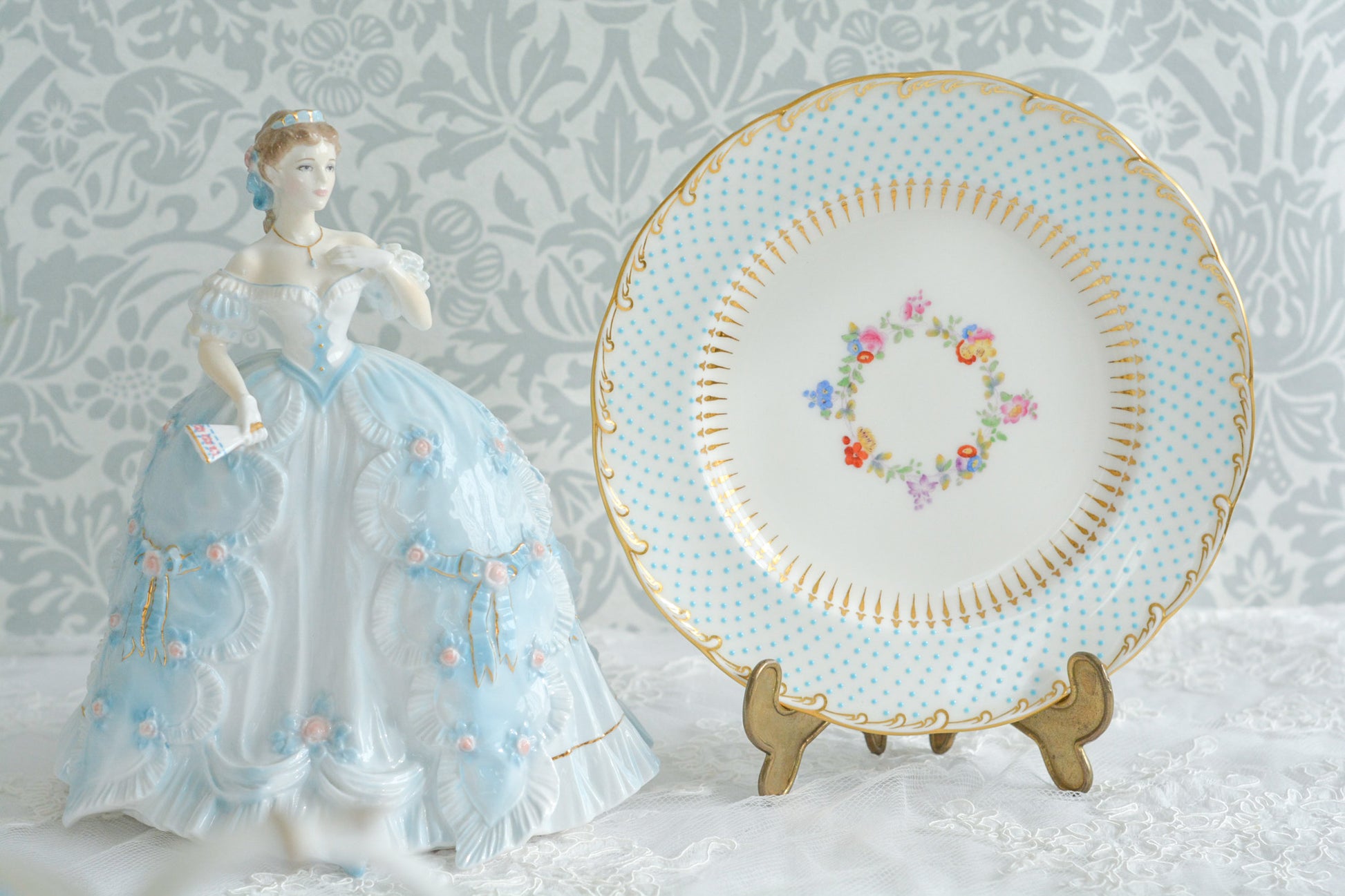 The First Quadrilleという題名のとても可愛らしいロイヤルウースターのフィギュリンです。フィギュリンの題名の通り「初めての舞踏会」に出たご令嬢がモデルになっています。可愛らしいお顔のお嬢様ですが、表情には少し緊張している様子がうまく表現されていると思いませんか?ドレスは爽やかな水色に大きなリボンと薔薇の花がたくさんついていて、舞踏会デビューを華やかに飾っています。とても可愛らしく、美しいフィギュリンでテーブルやお部屋に花を添えてくれます。
