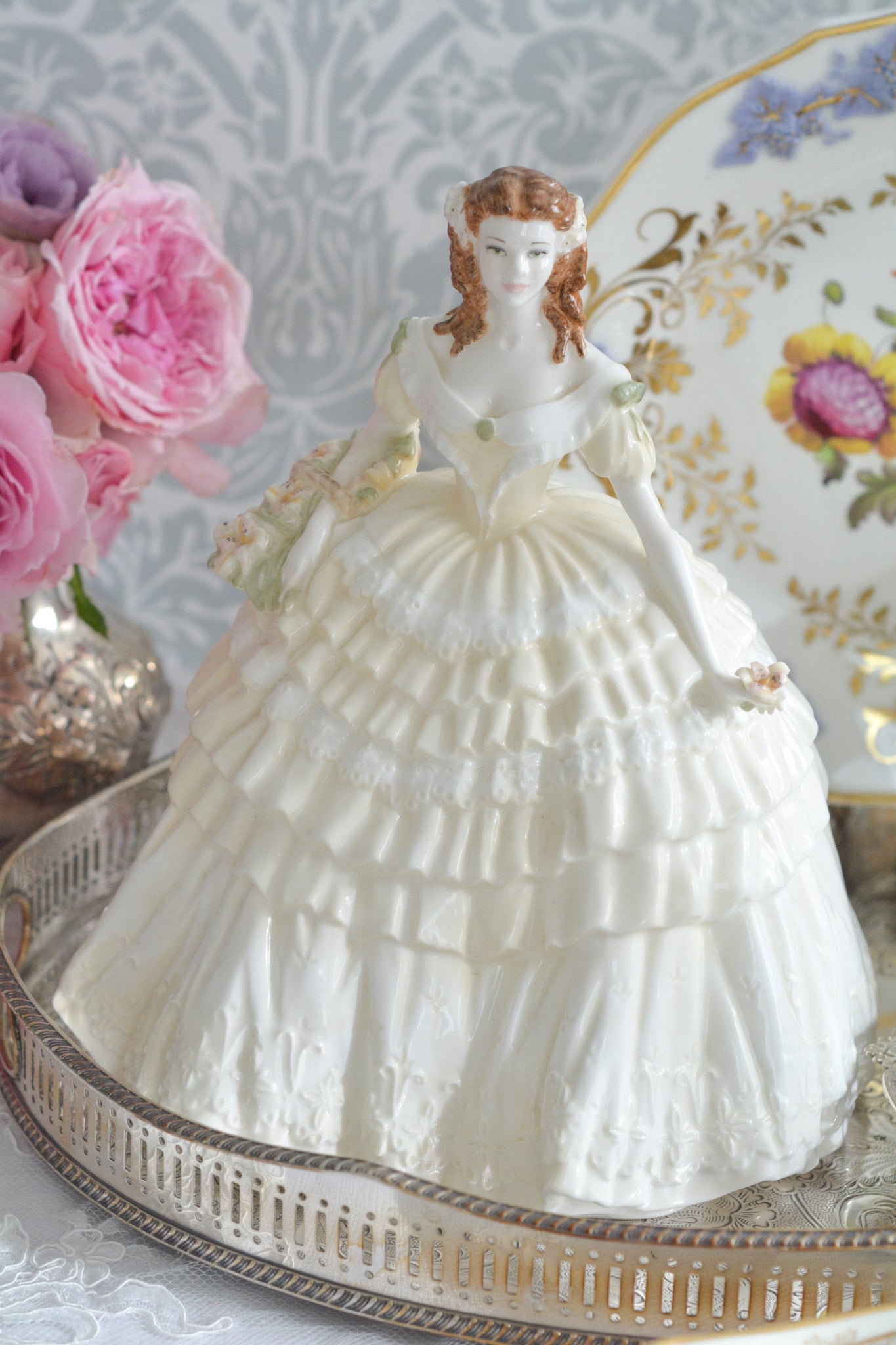 コールポートの人気フィギュリン、「The Four Flowers Collection」。名前の通り、「リリー、ローズ、カーネション、アイリス」の4つのお花がモチーフのフィギュリンシリーズです。 その中でも、リリーはアイリスと並び入手困難なお品です。  バスケットいっぱいのリリーと左手には一輪のリリーの花。ドレスはホワイトに淡いイエローのフリルとグリーンのリボンがあしらわれています。 柔らかな表情がとても可愛らしいレディのフィギュリンです。