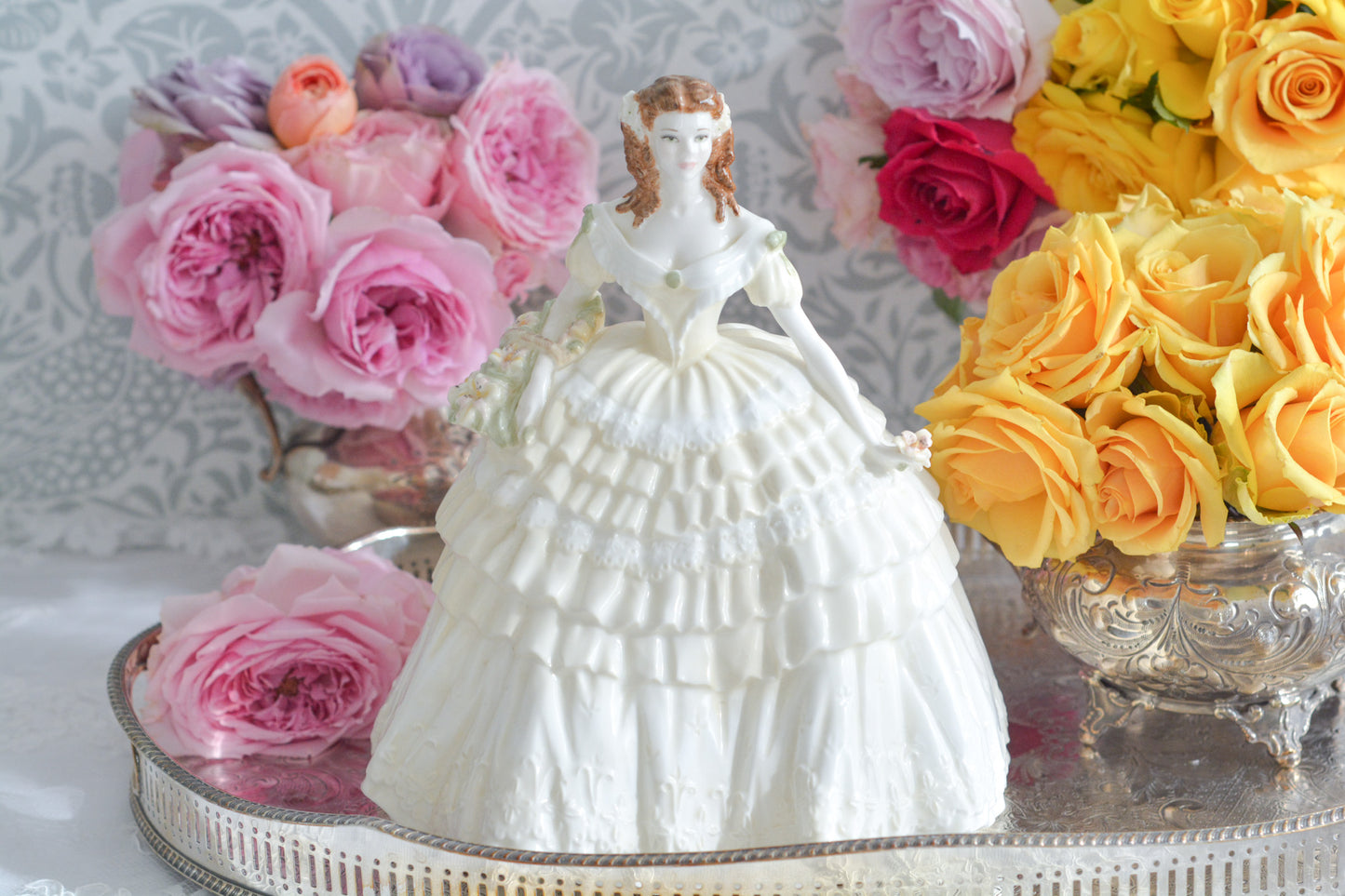 コールポートの人気フィギュリン、「The Four Flowers Collection」。名前の通り、「リリー、ローズ、カーネション、アイリス」の4つのお花がモチーフのフィギュリンシリーズです。 その中でも、リリーはアイリスと並び入手困難なお品です。 バスケットいっぱいのリリーと左手には一輪のリリーの花。ドレスはホワイトに淡いイエローのフリルとグリーンのリボンがあしらわれています。 柔らかな表情がとても可愛らしいレディのフィギュリンです。