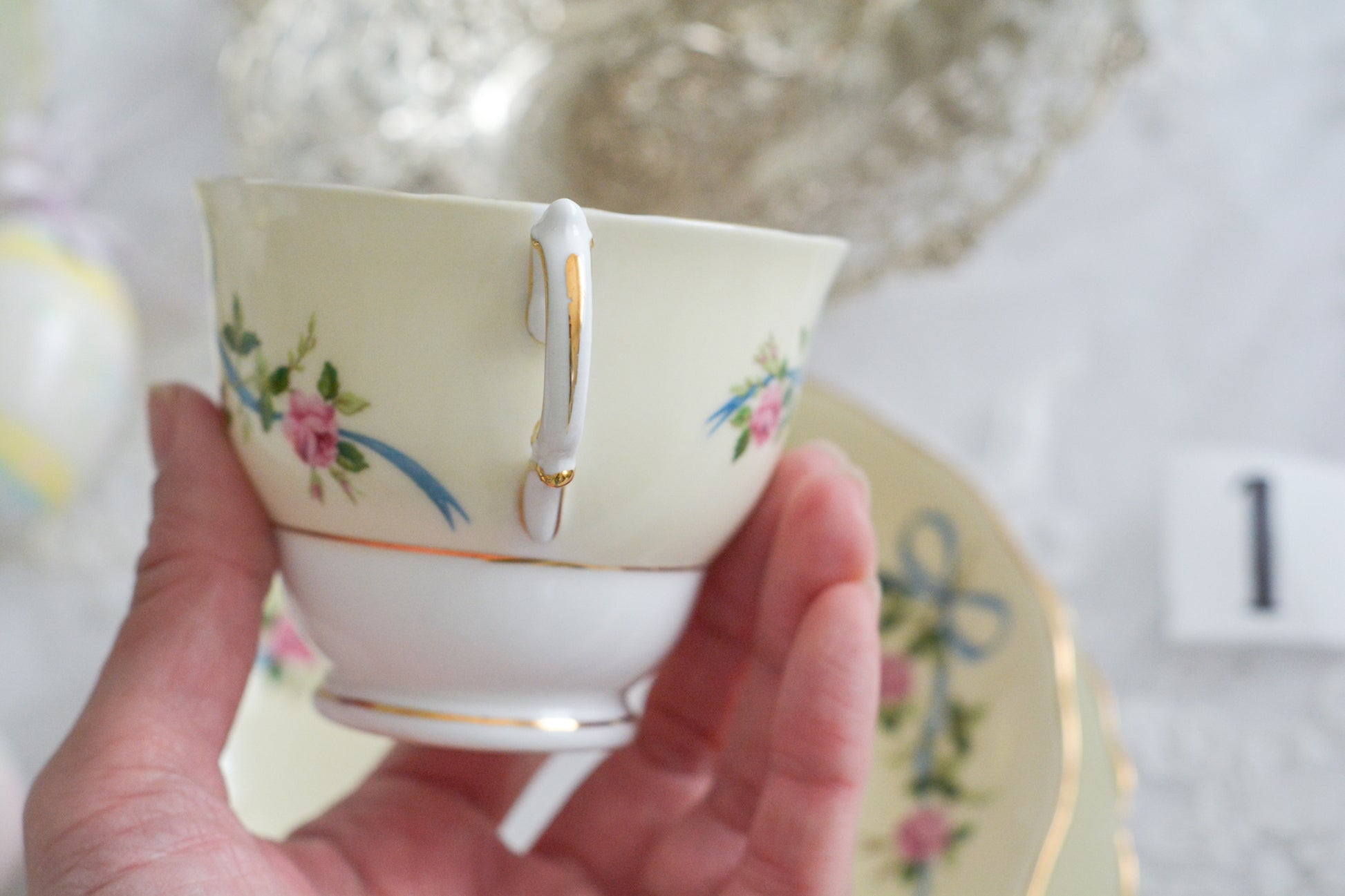 コルクラフ(Colclough)の可愛らしいティートリオ。コルクラフは1890年にハーバード・ジョセフ・コルクラフ氏が創業したメーカで、1940年代頃まで続いていました。コルクラフの中でもこのリボンの絵柄は人気で入手困難なお品です。クリーム色にブルーリボンと小さなバラの模様がとっても可愛らしいデザインです。パステルカラーがイースターや春のティータイムにもぴったりですね!